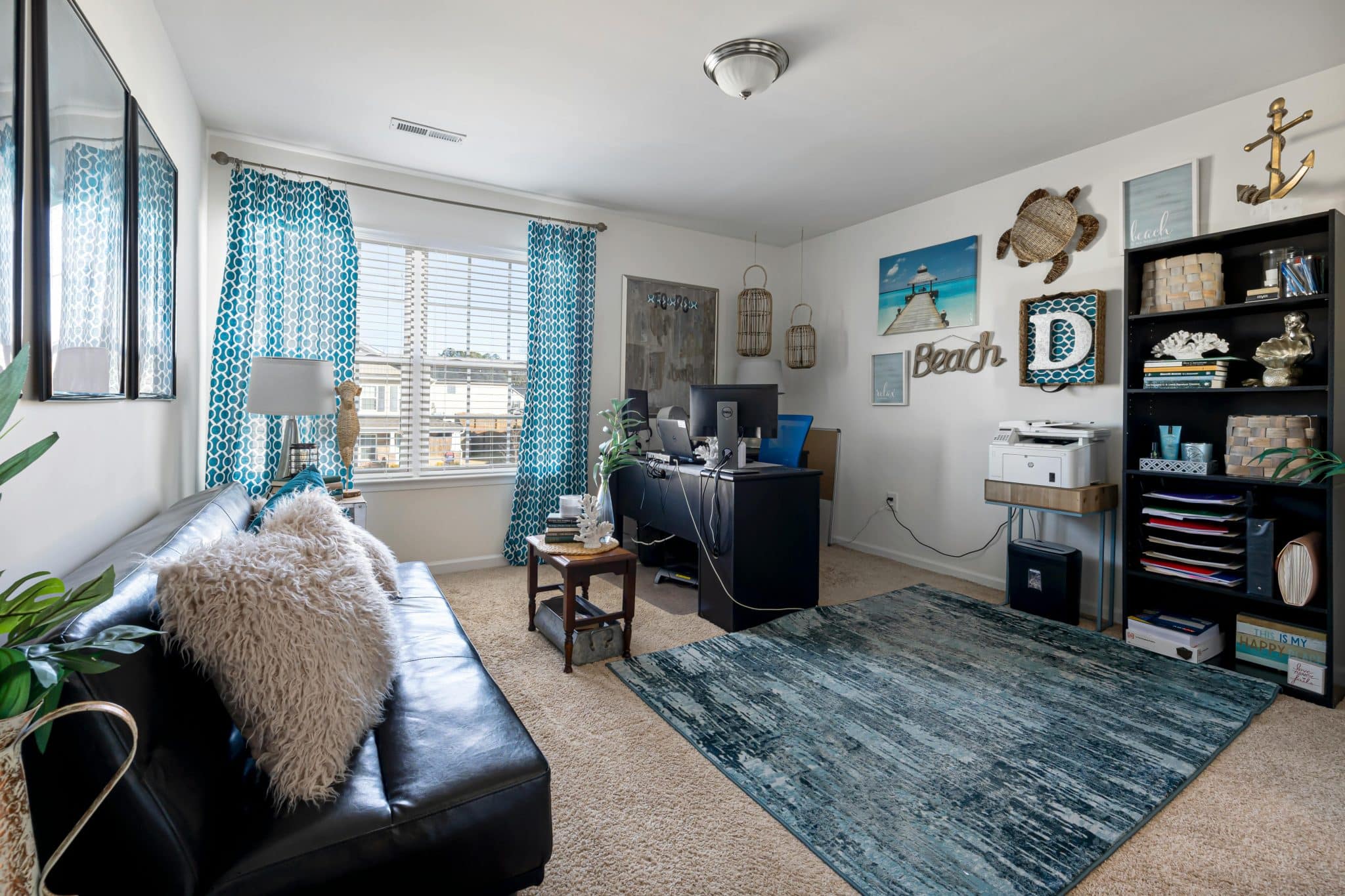 Stylish beach-themed living room with home office setup, combining comfort and functionality.