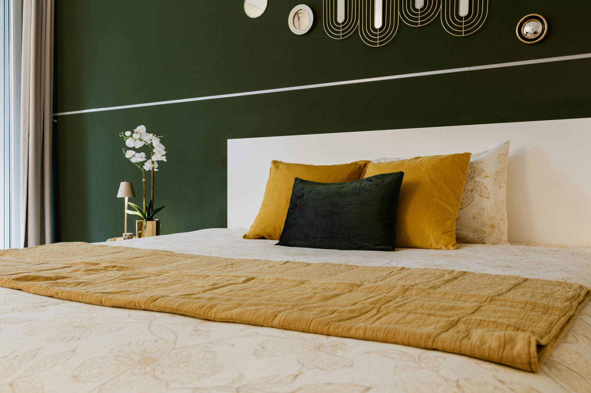 Stylish bedroom design featuring green walls, yellow pillows, and geometric wall art. Perfect for modern home decor inspiration.