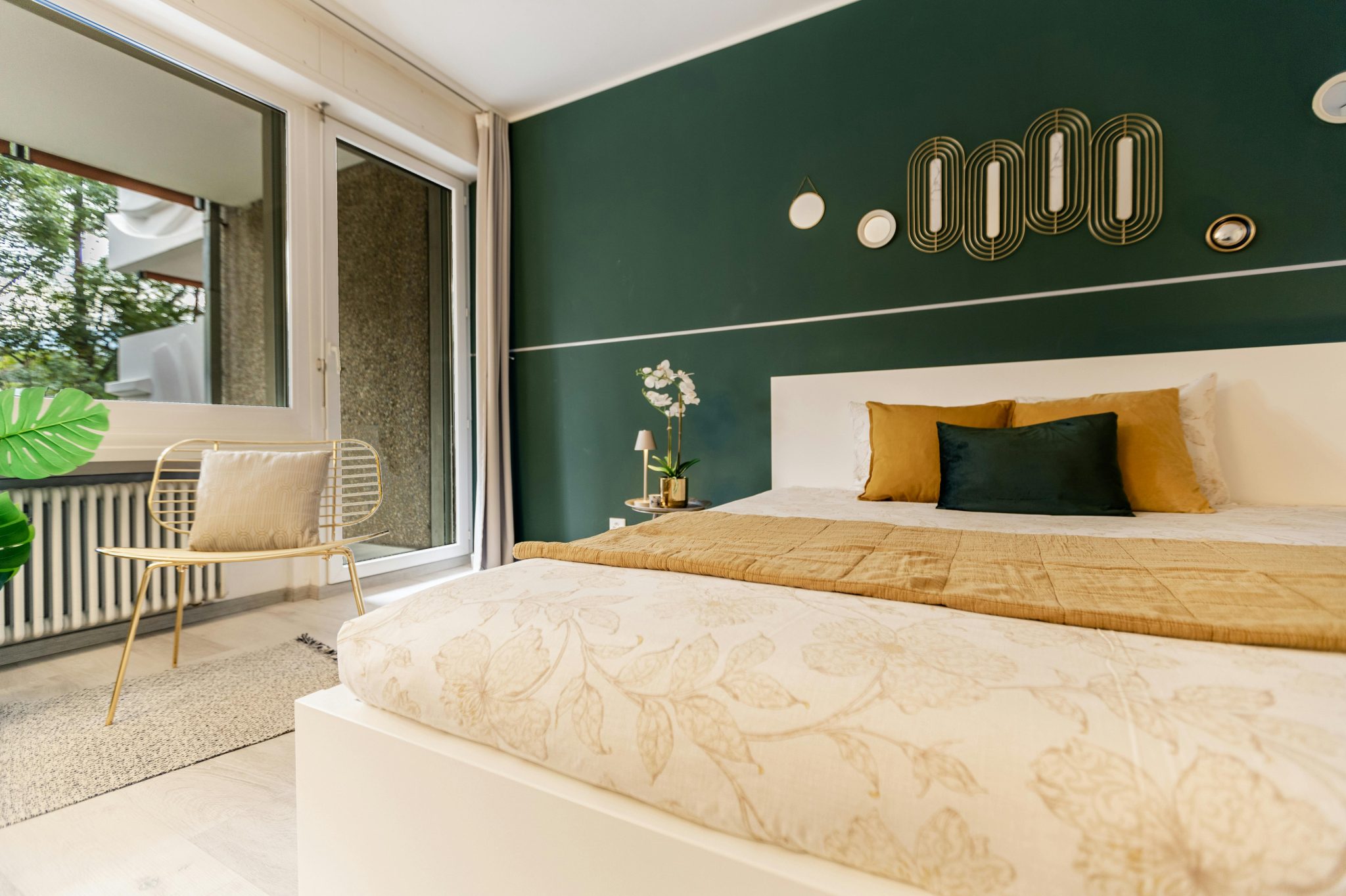 Stylish bedroom featuring a green accent wall, cozy bed, and contemporary decor in natural light.