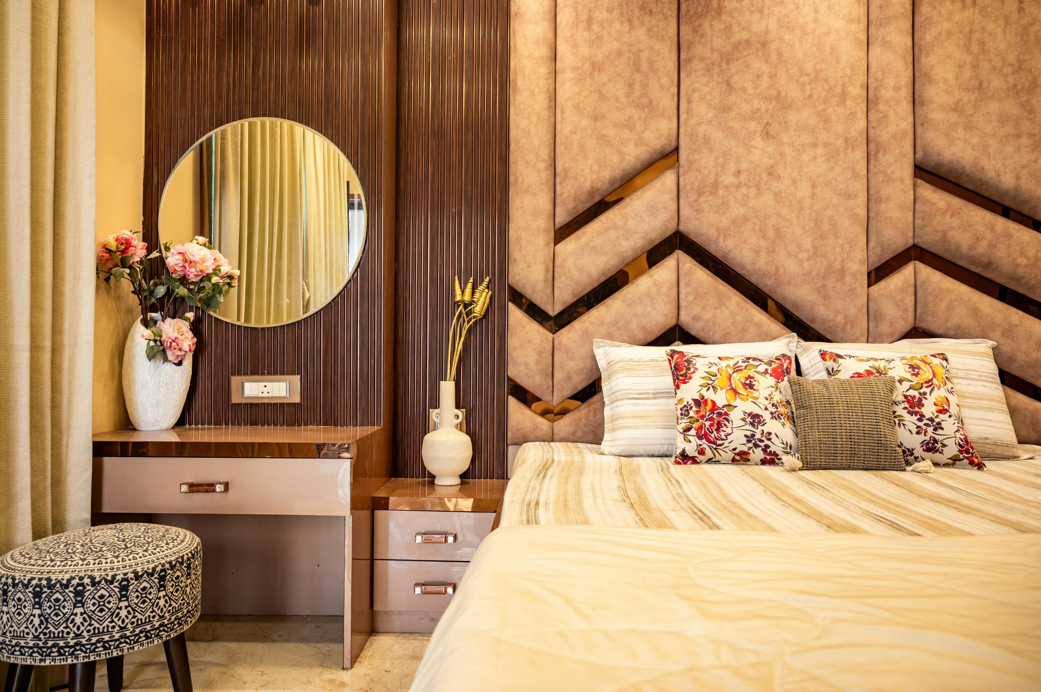 Stylish bedroom interior featuring a cozy bed, floral pillows, and a chic vanity setup.