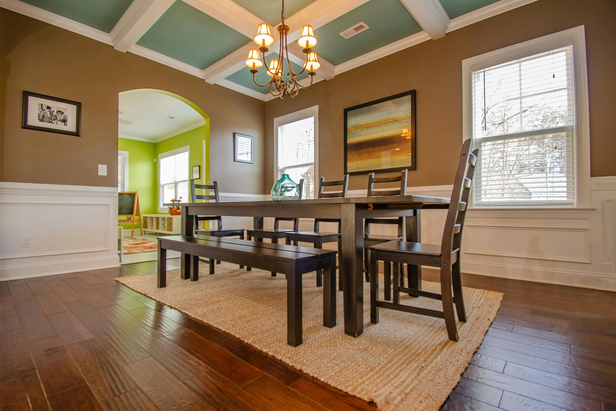 Stylish dining room featuring modern wood furniture, large windows, and artistic decor.