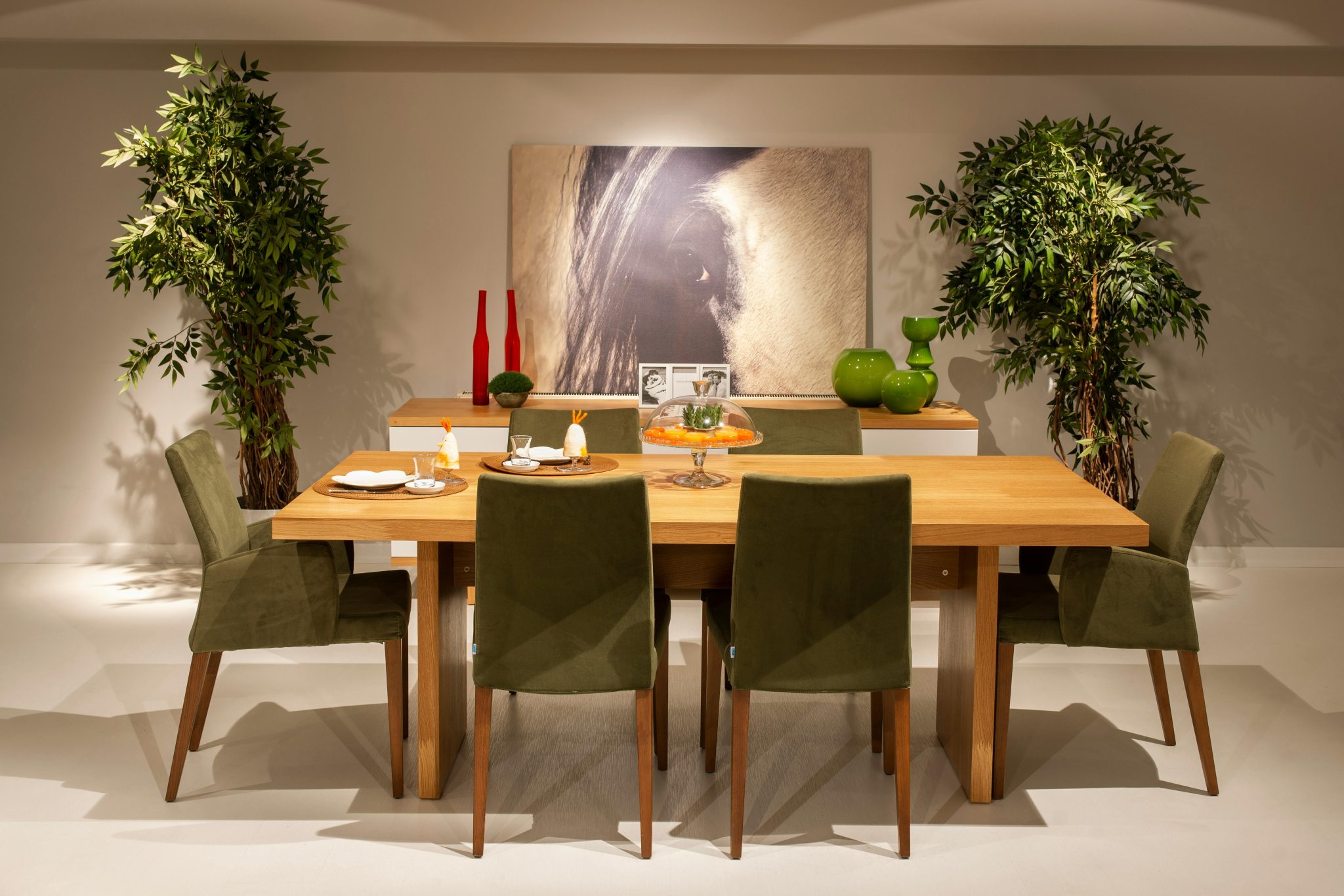 Stylish dining room setup with a wooden table and green chairs in a modern interior design.