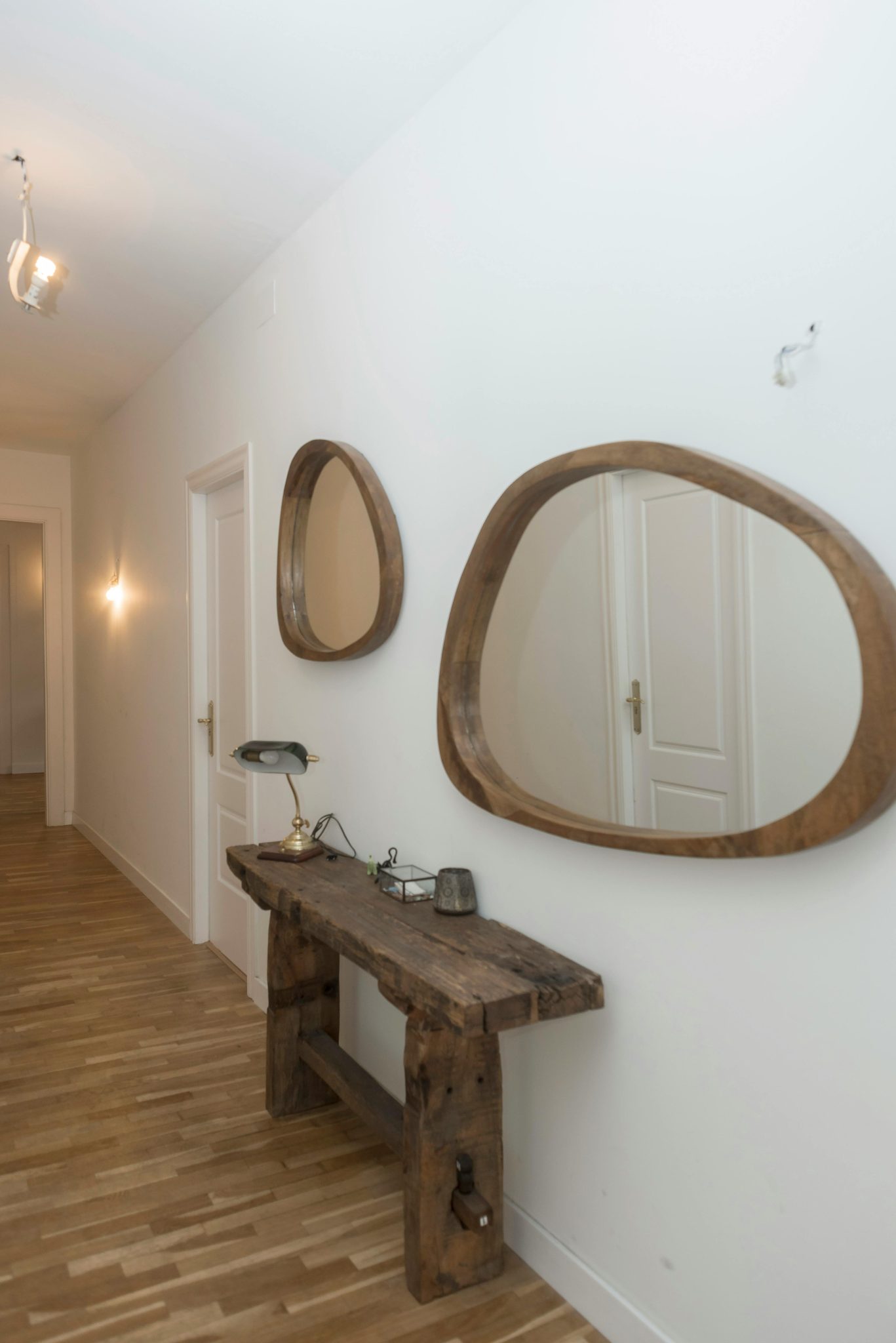 Stylish hallway with wooden mirrors and console table on white walls.