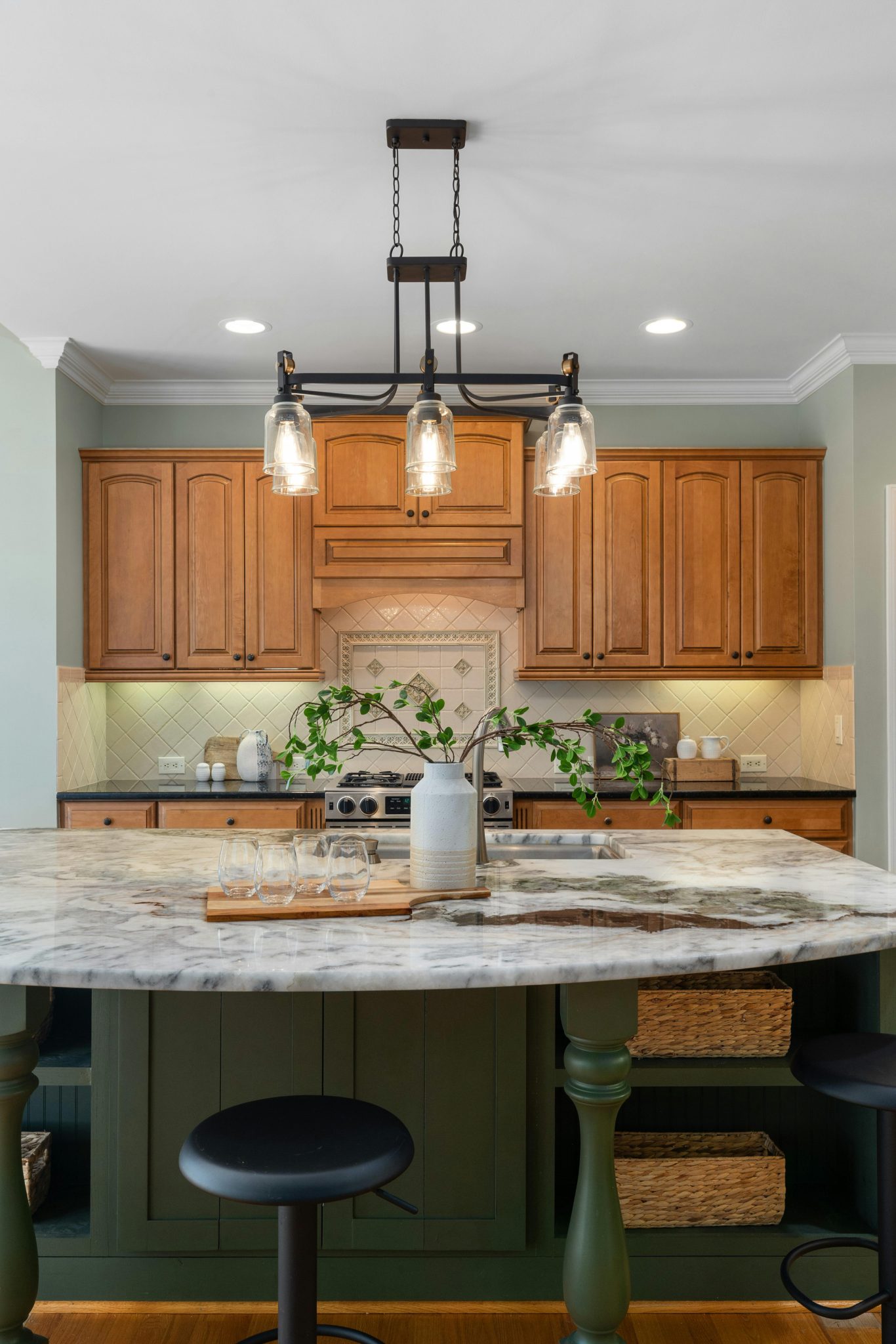Stylish kitchen featuring a marble top island, wooden cabinets, and modern lighting.