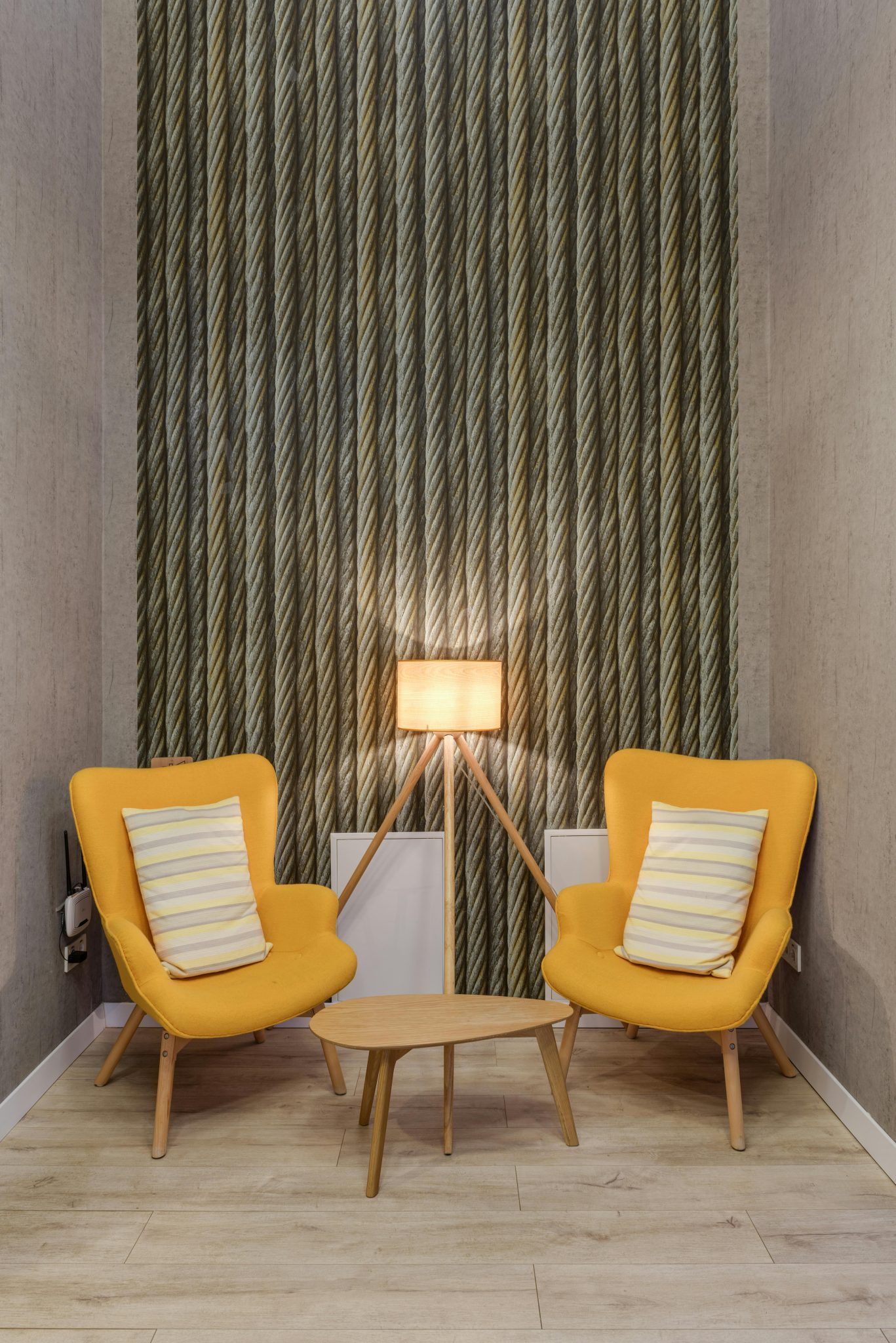 Stylish seating area with yellow chairs, wooden table, and lamp.