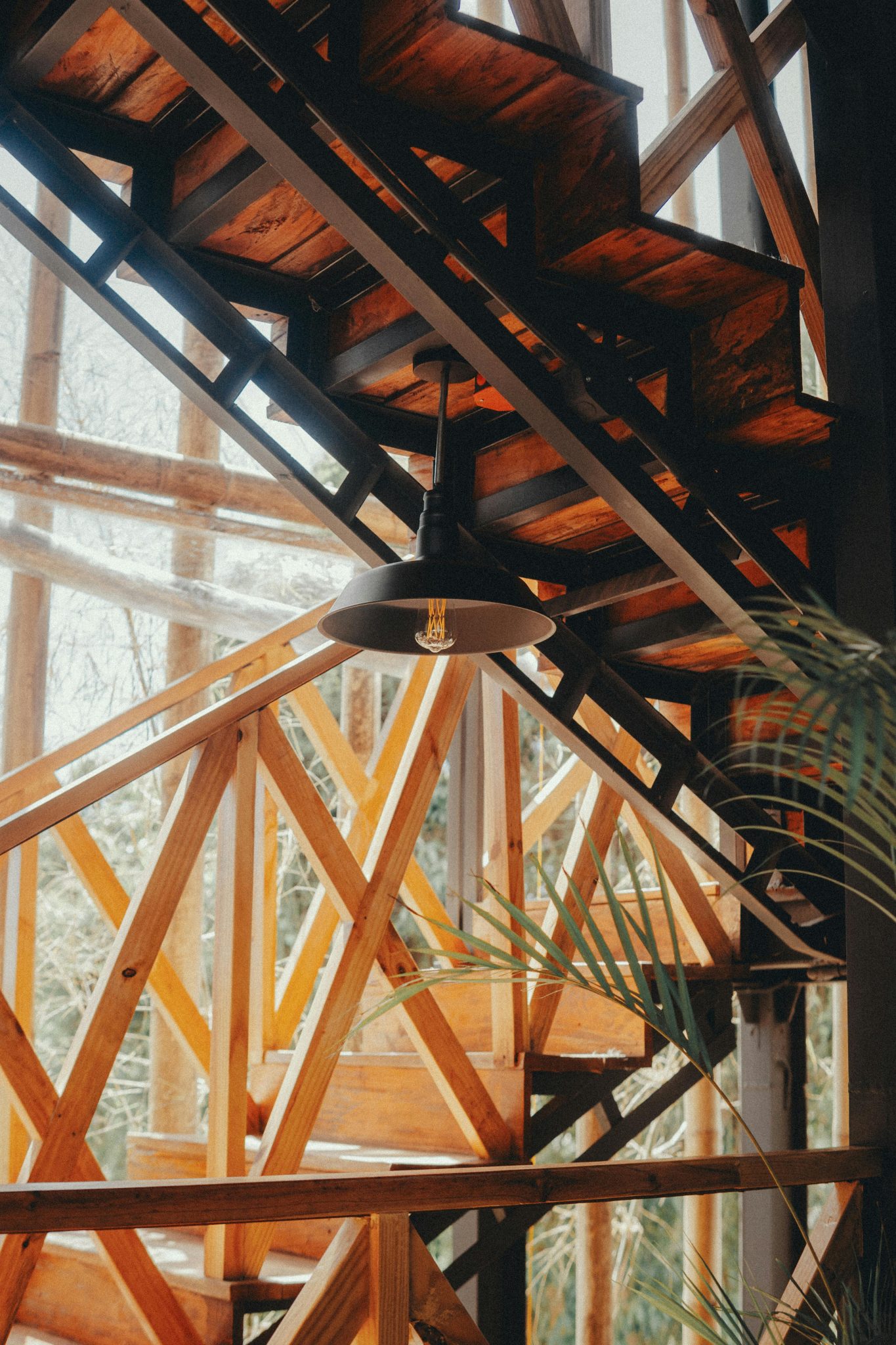 Stylish wooden staircase with geometric design and industrial lighting in a modern interior.