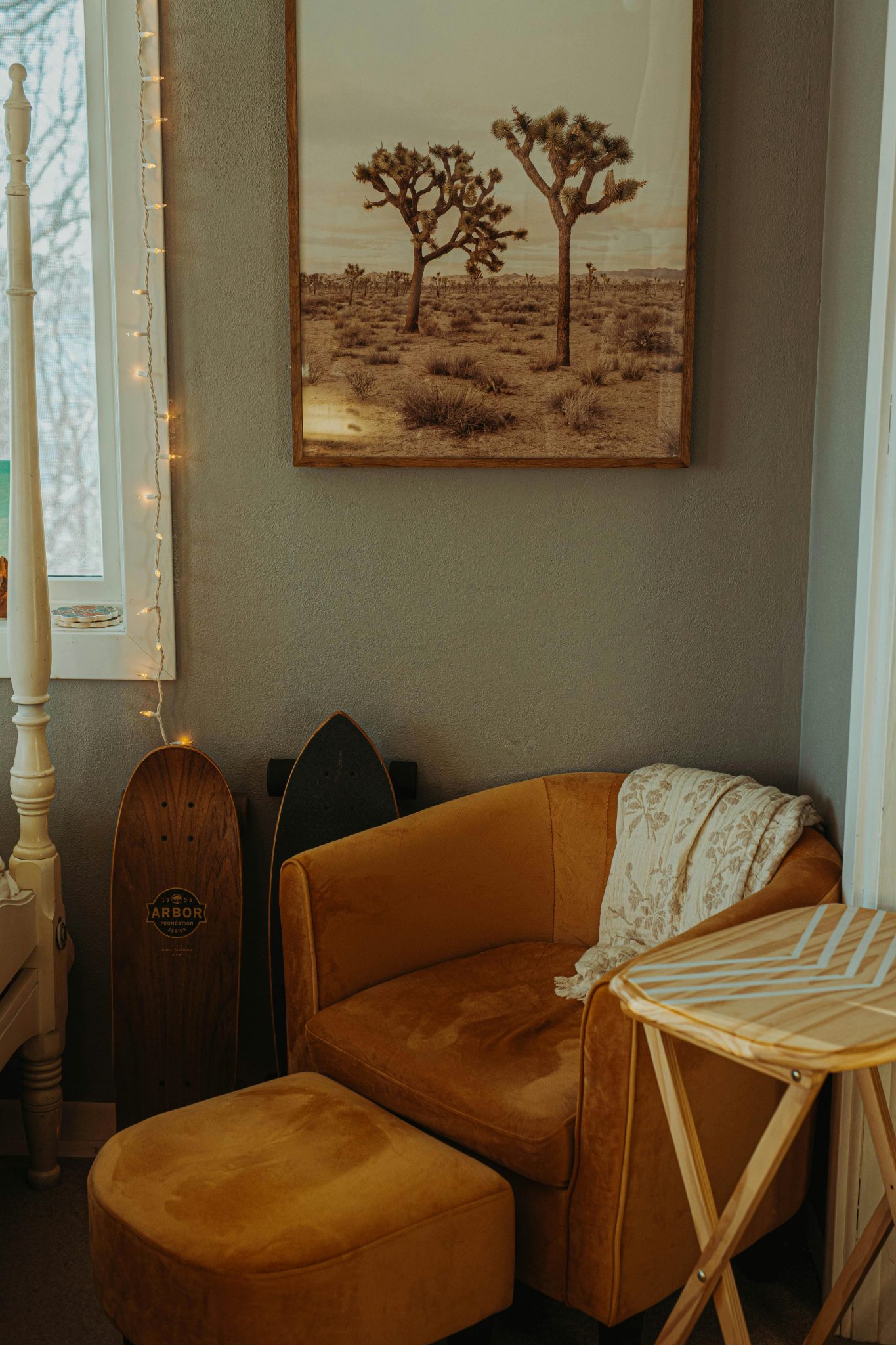 Warm and cozy interior featuring a mustard armchair, skateboard, and desert-inspired wall art.