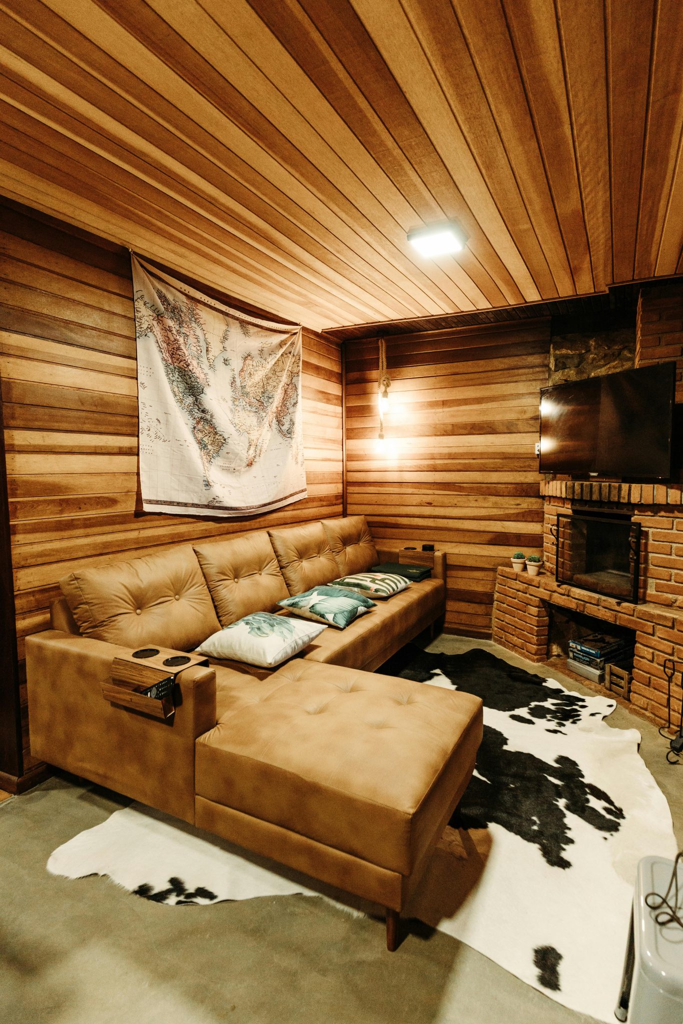 Warm and inviting wooden living room with a leather sofa and brick fireplace, perfect for relaxation.