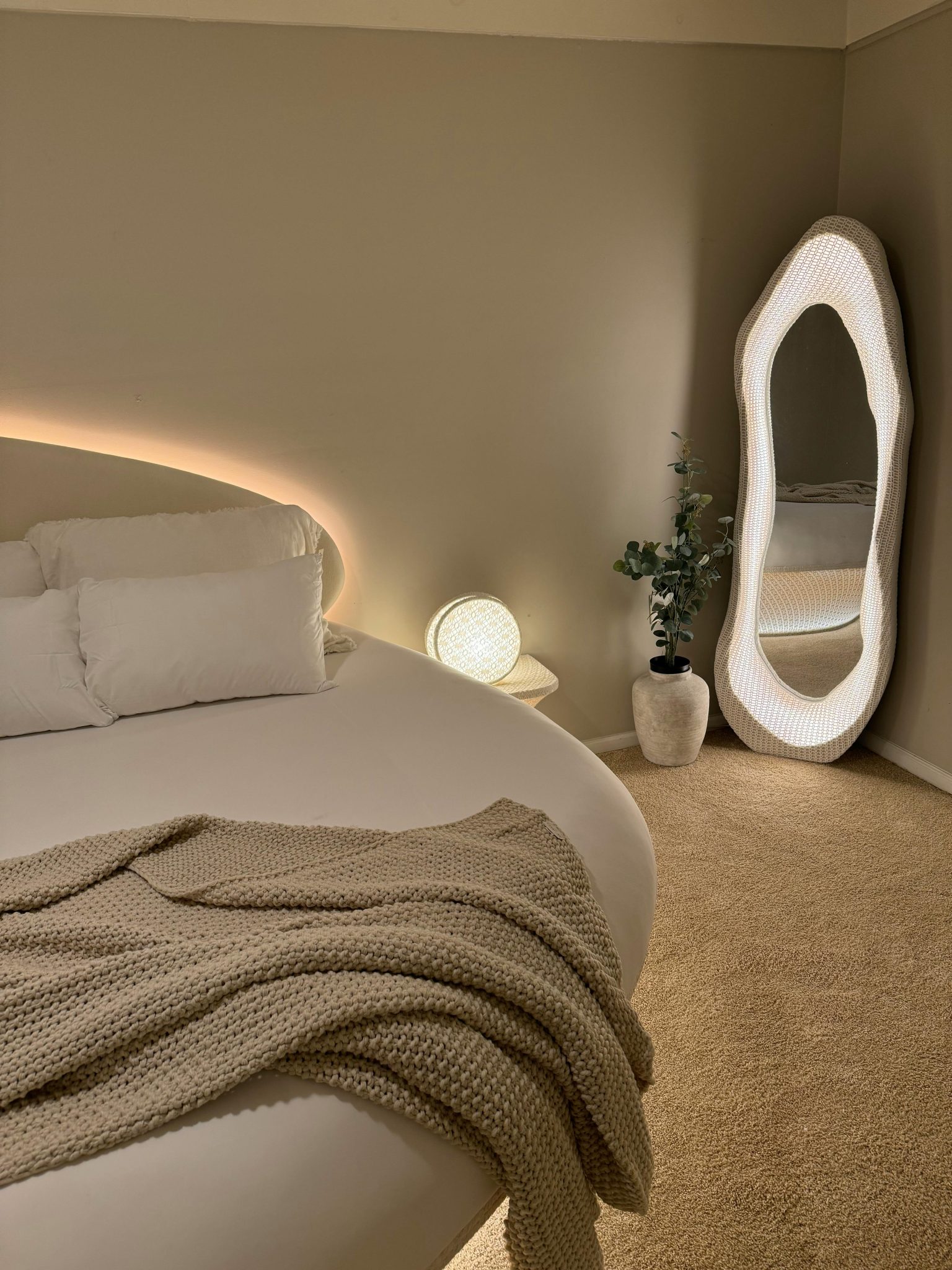 Warm, inviting bedroom featuring a unique floor mirror and ambient lighting for a cozy ambiance.