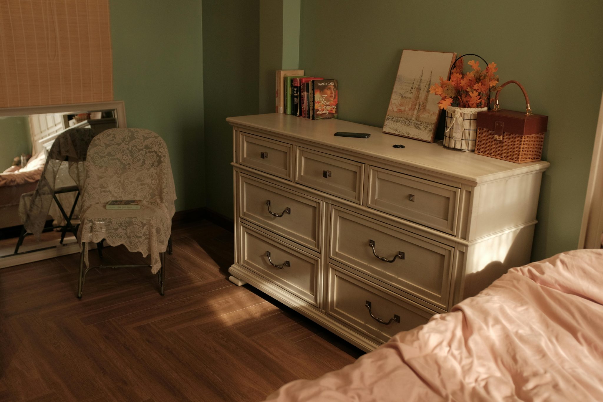 Warm-toned bedroom showcasing vintage decor with a dresser and lace-covered chair.