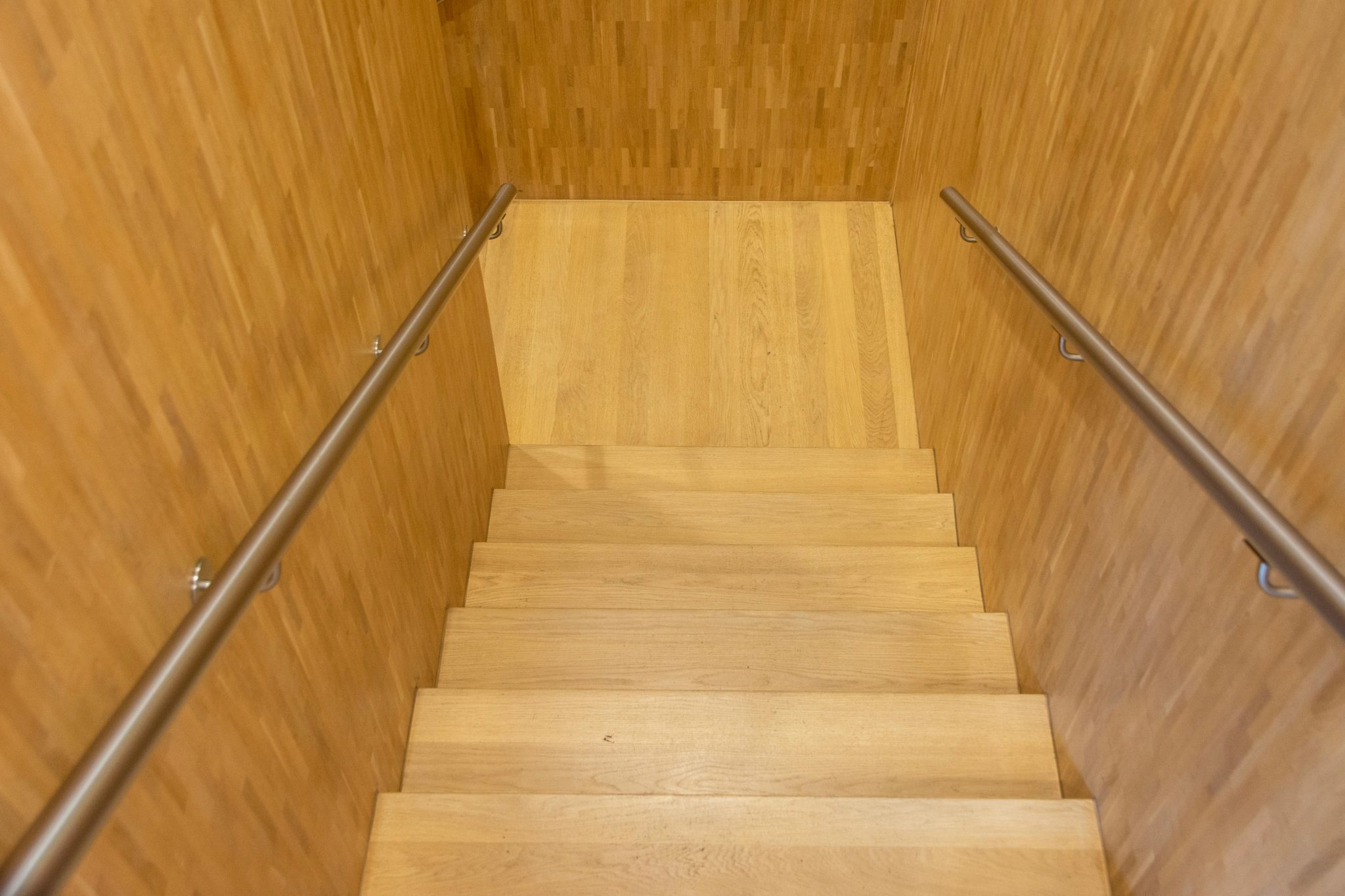 Warm wooden staircase view with metal railings, perfect for modern interiors.