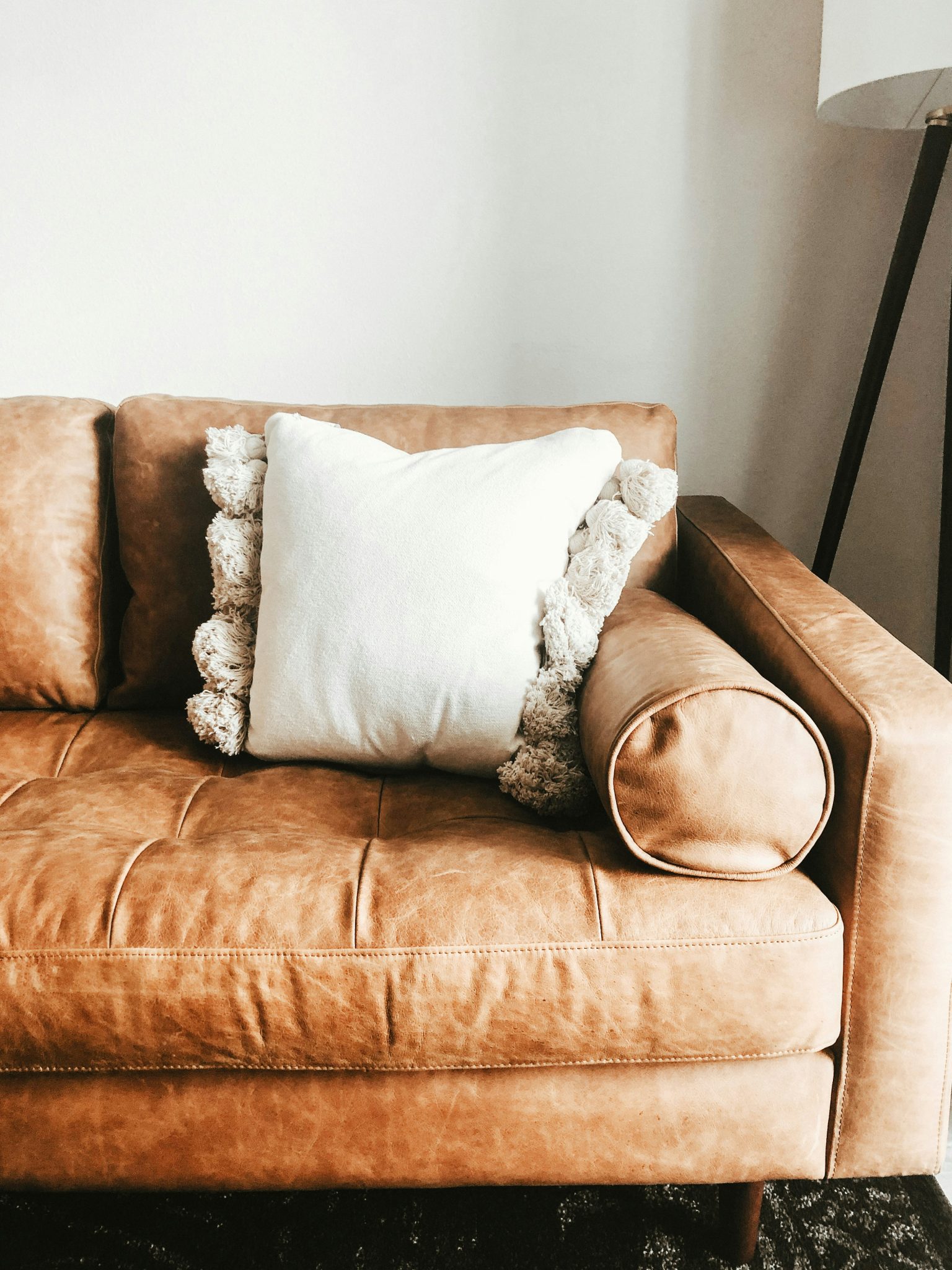 White pillow on a cozy leather couch.