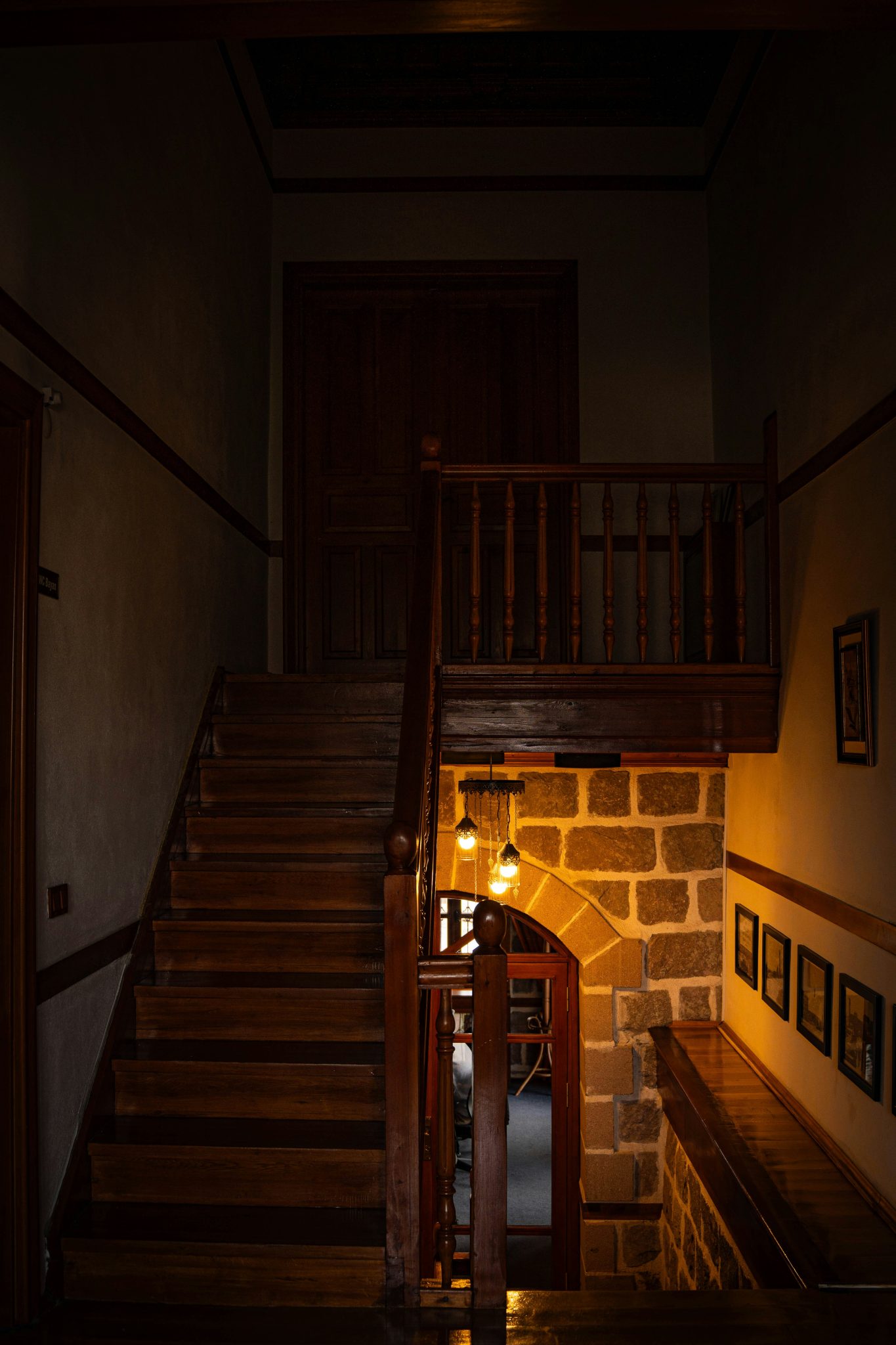 Wooden staircase with stone archway and hanging lights