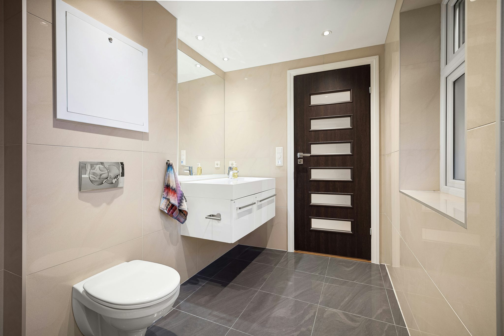 A bathroom with a toilet, sink, and mirror
