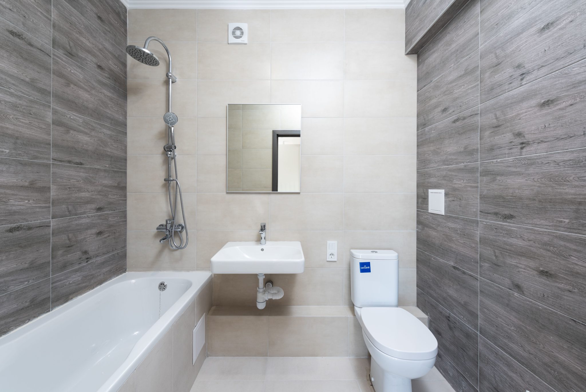 A contemporary bathroom features a bathtub, sink, and toilet with wood accents.