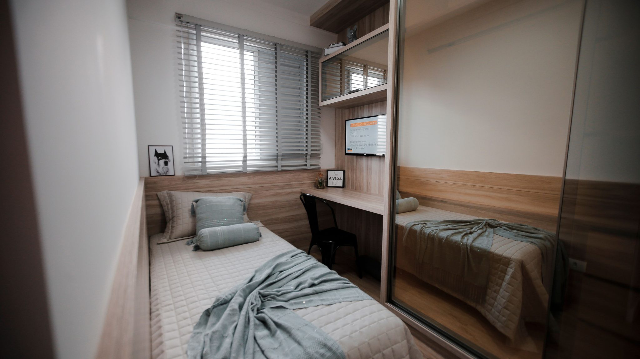 A cozy and minimalist bedroom interior featuring a single bed and a small workspace.