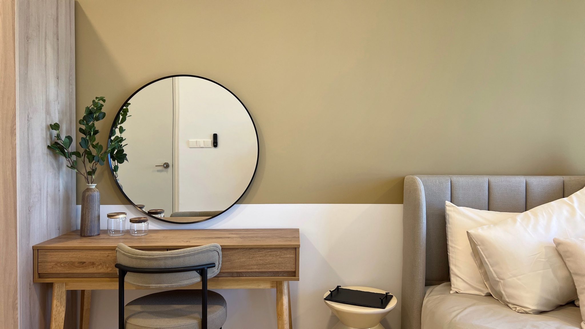 A cozy bedroom featuring a wooden vanity, mirror, and soft textiles, perfect for modern interior design.
