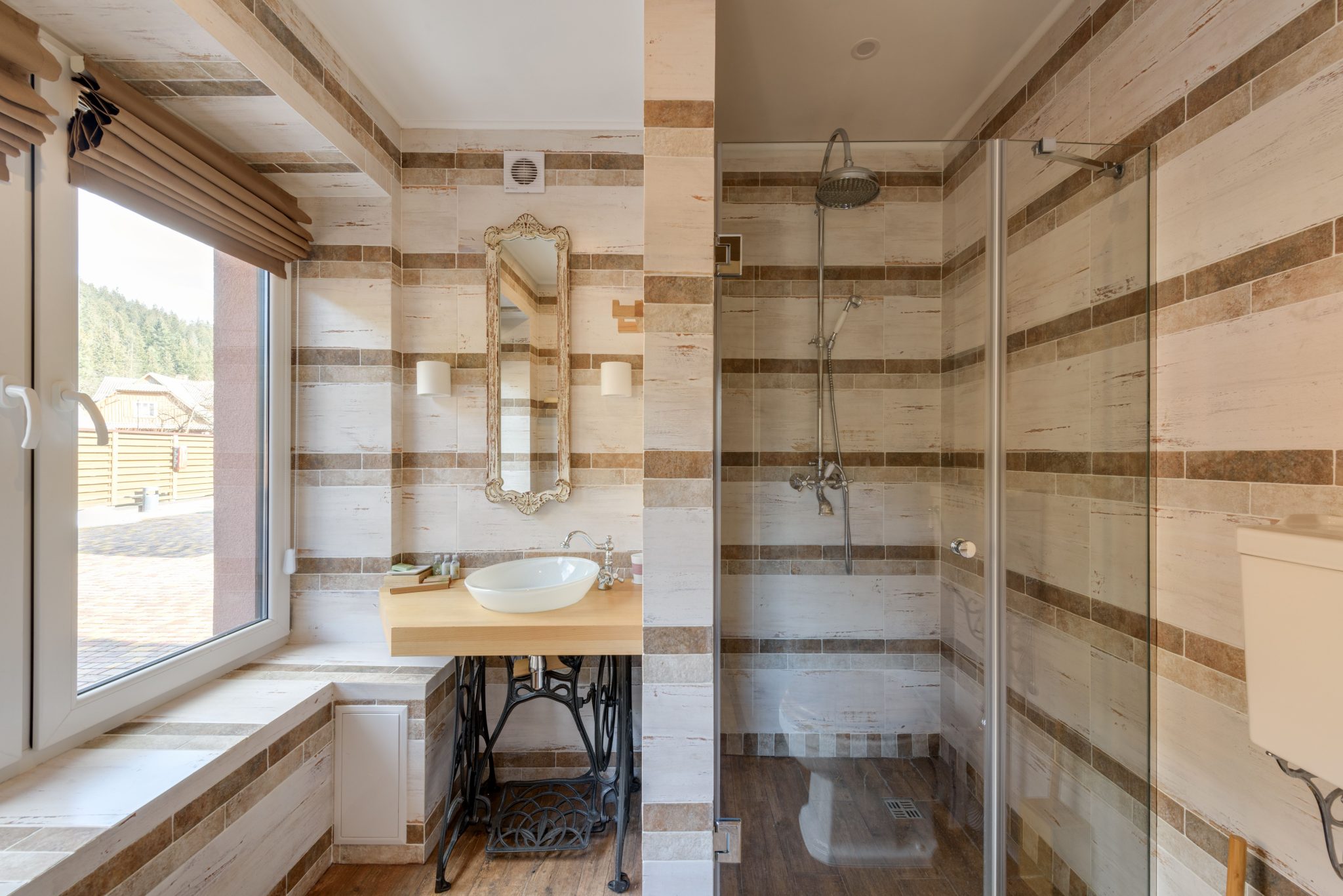A stylish bathroom featuring a rustic vanity and a glass shower with natural light.