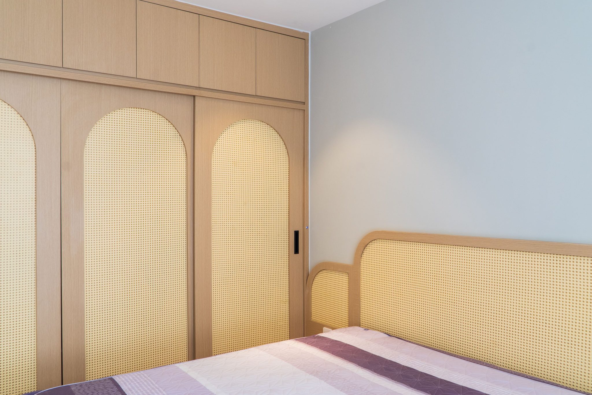 A stylish bedroom featuring a contemporary woven wardrobe and matching headboard design.