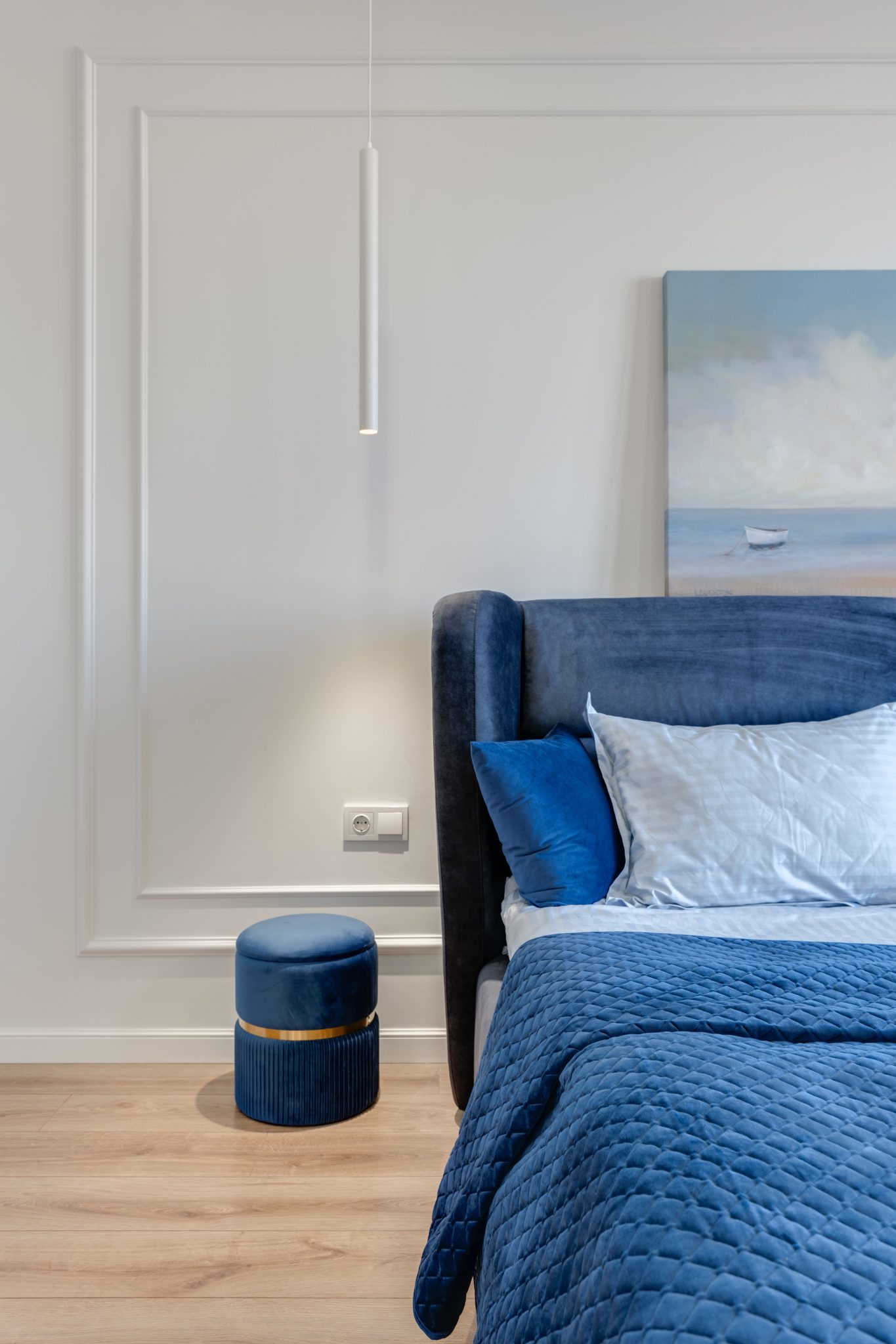 A stylish bedroom with blue quilted bedding and wall art, offering a modern and serene vibe.