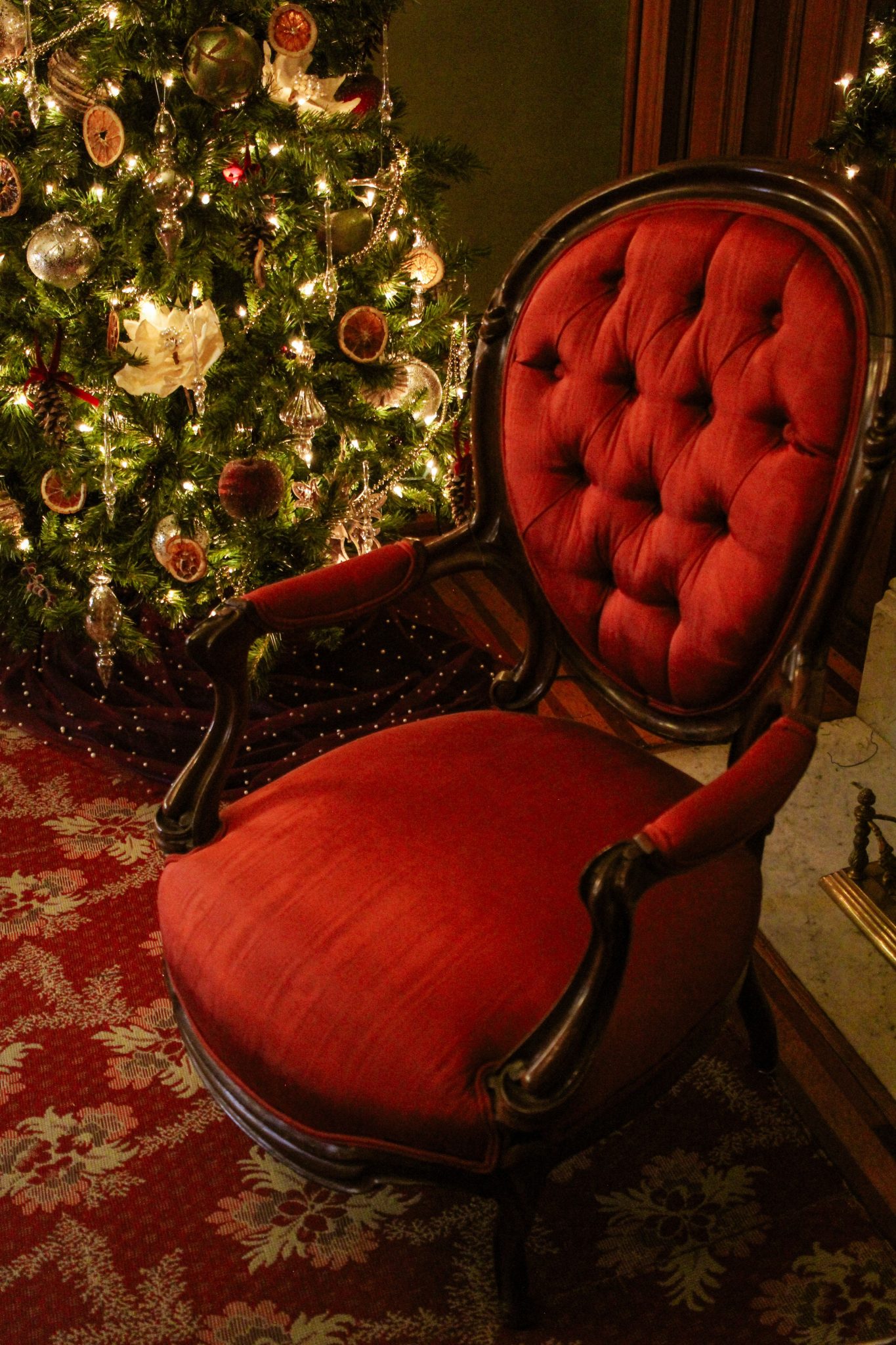 A vintage red chair beside a beautifully decorated Christmas tree indoors.