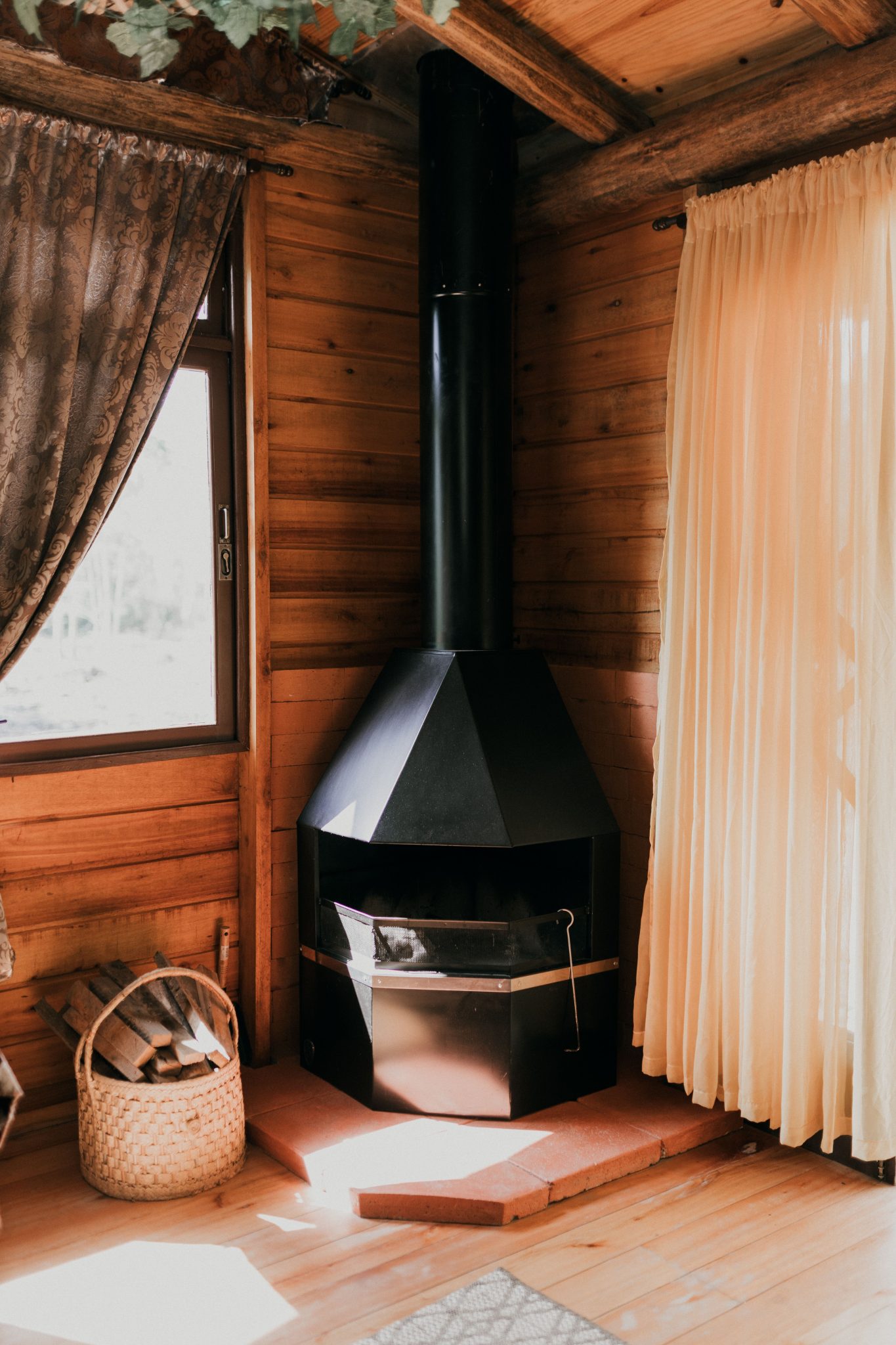 A warm and rustic cabin interior featuring a modern wood stove and soft natural lighting.