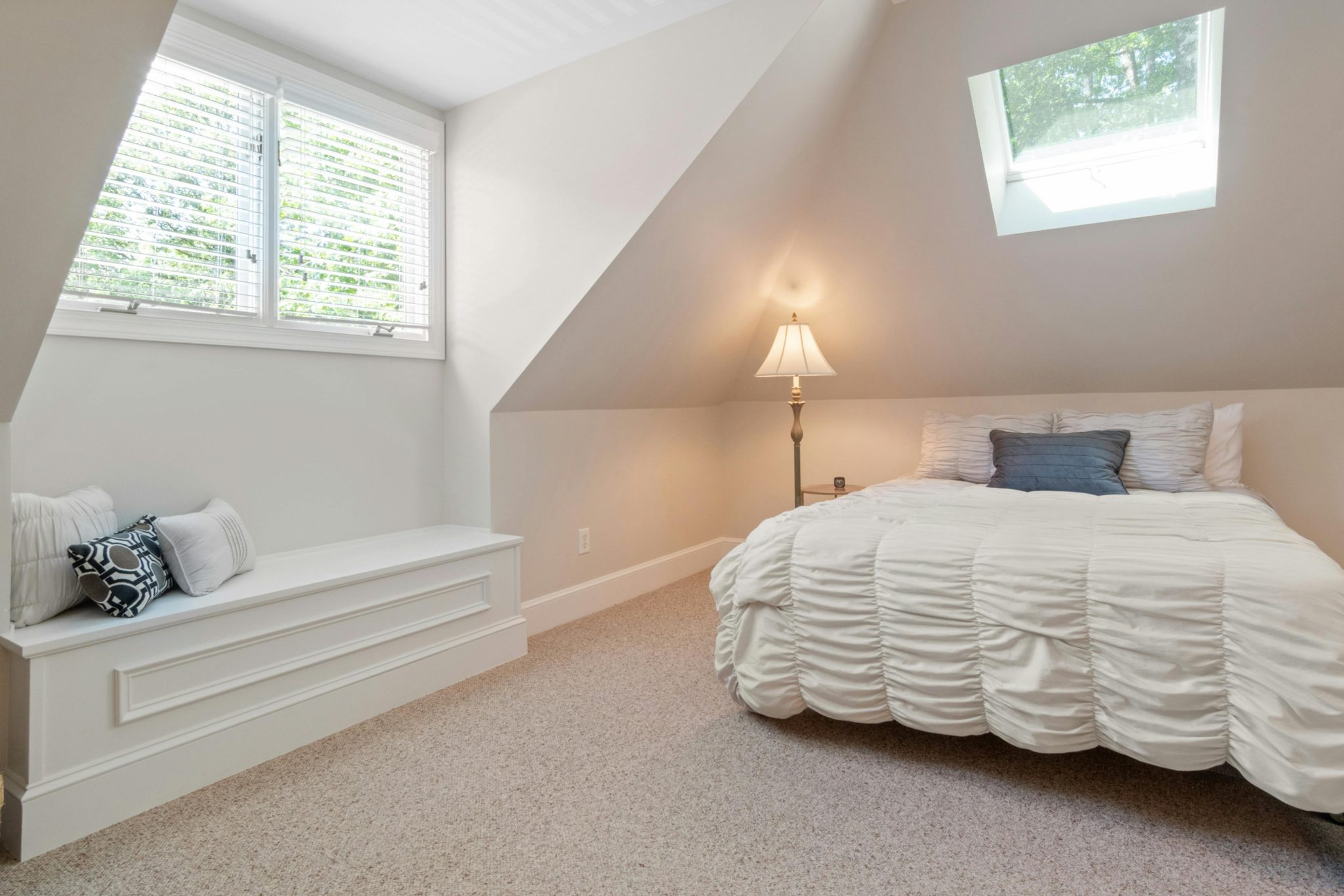 Charming attic bedroom featuring a cozy bed, natural light, and elegant interior design.