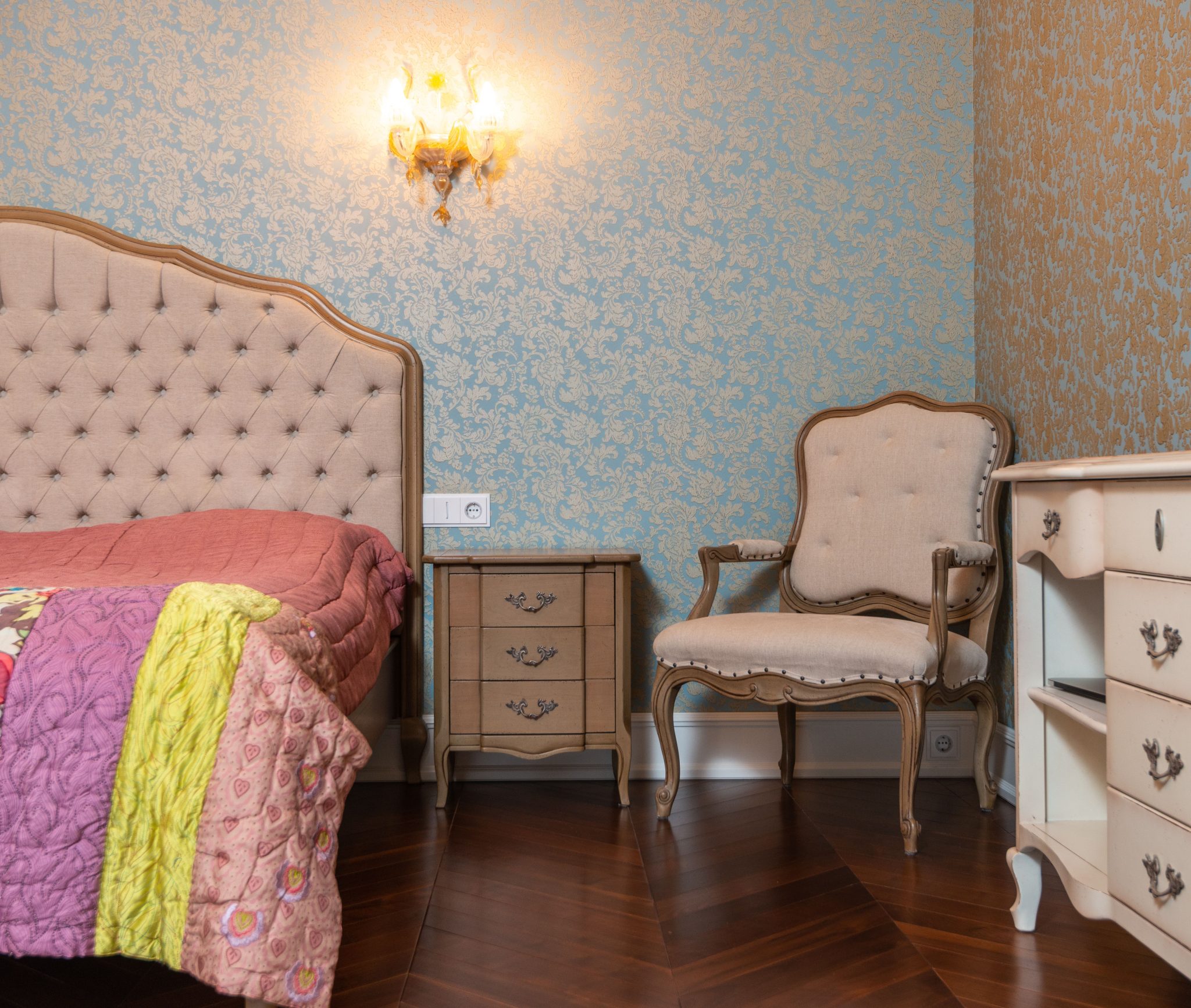 Chic bedroom decor featuring vintage furniture, patterned wallpaper, and cozy lighting.