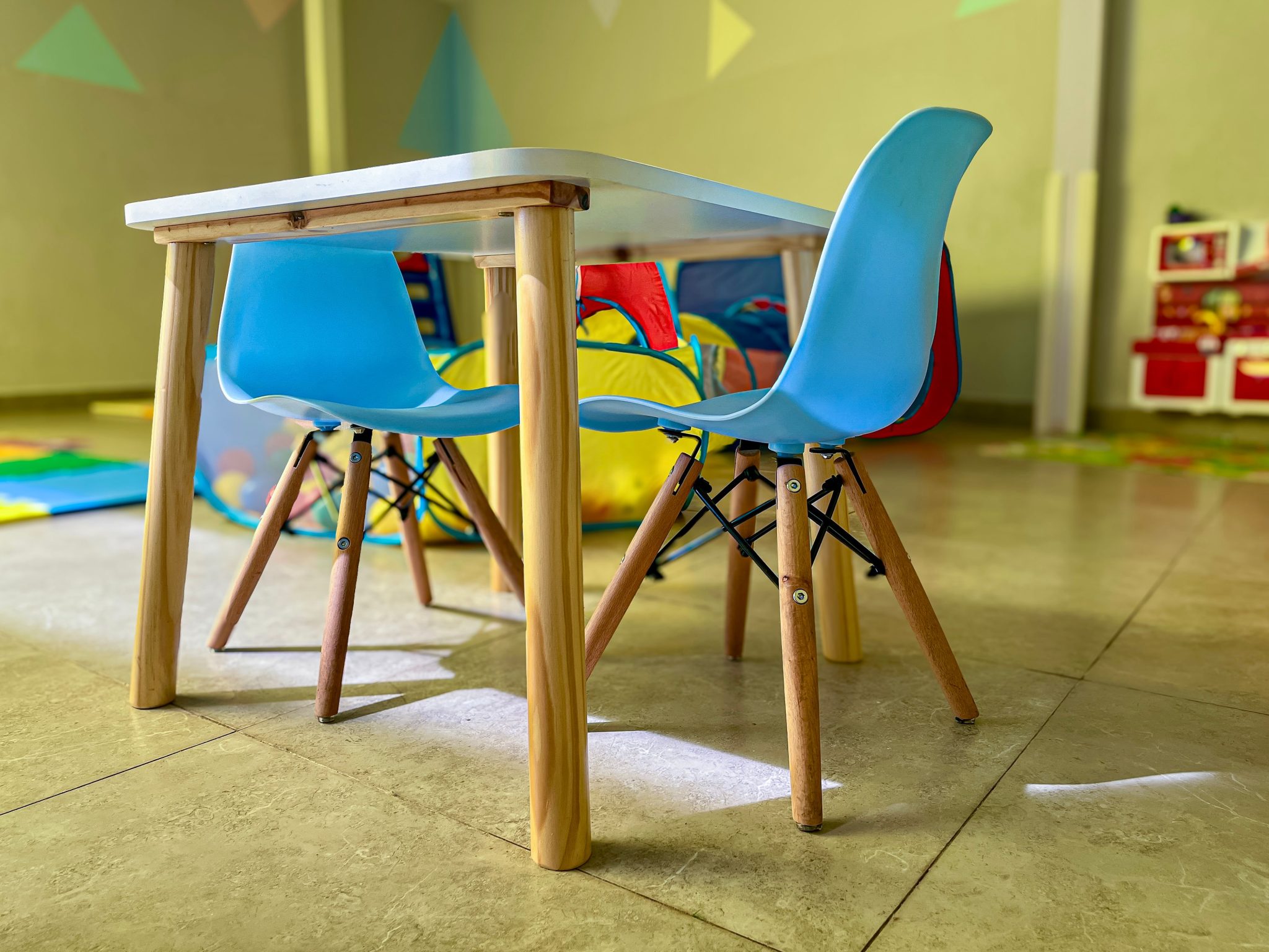Colorful and inviting kiddie area with modern chairs and a sturdy table in a vibrant playroom.