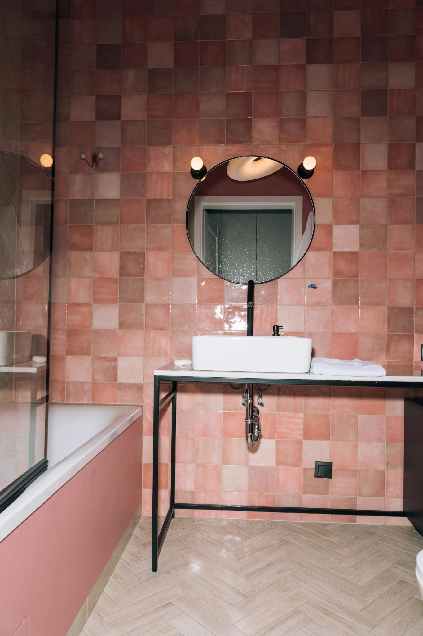 Contemporary pink bathroom featuring elegant decor and a round mirror.