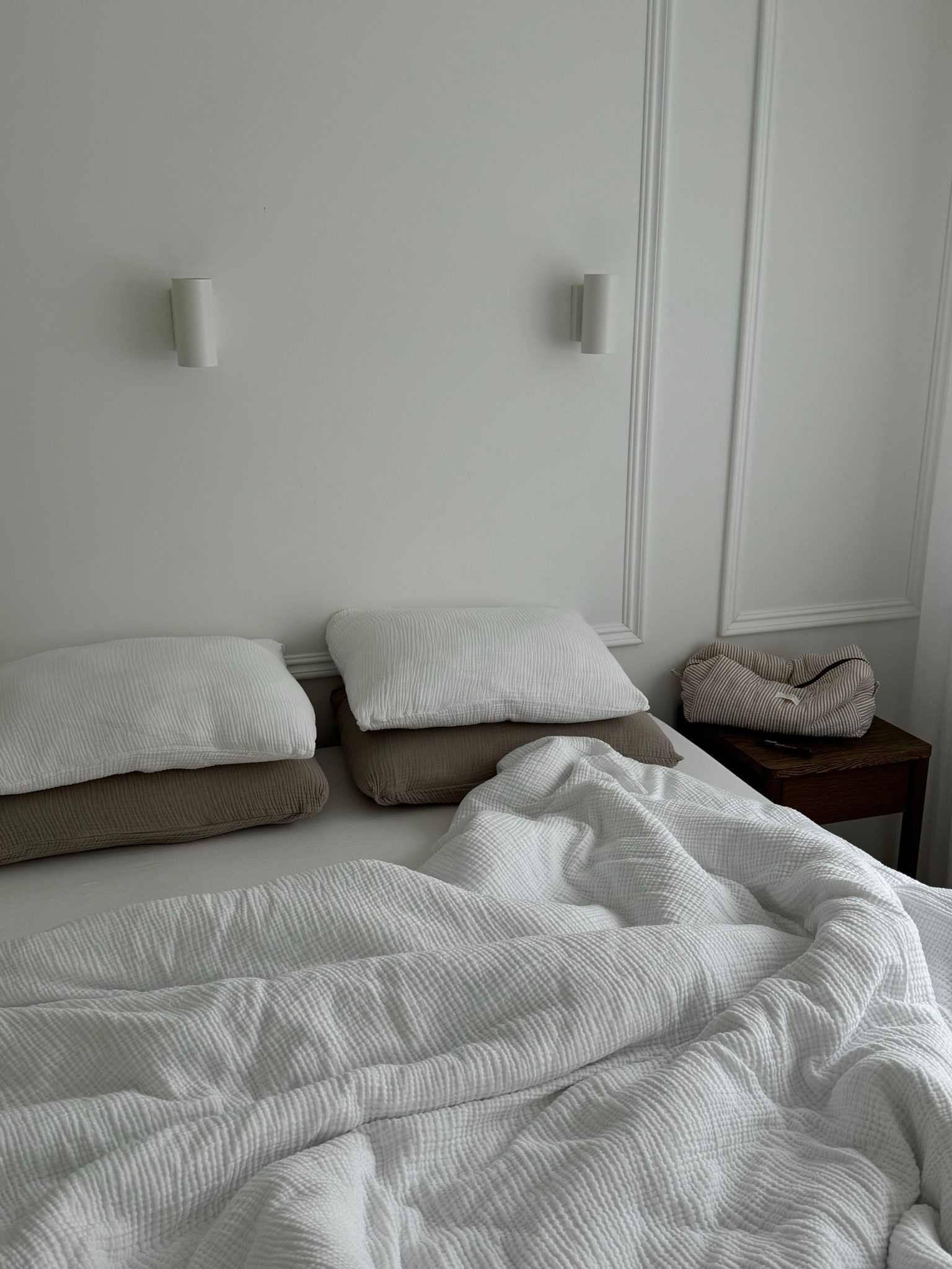 Cozy and inviting minimalist white bedroom with crumpled bedding.