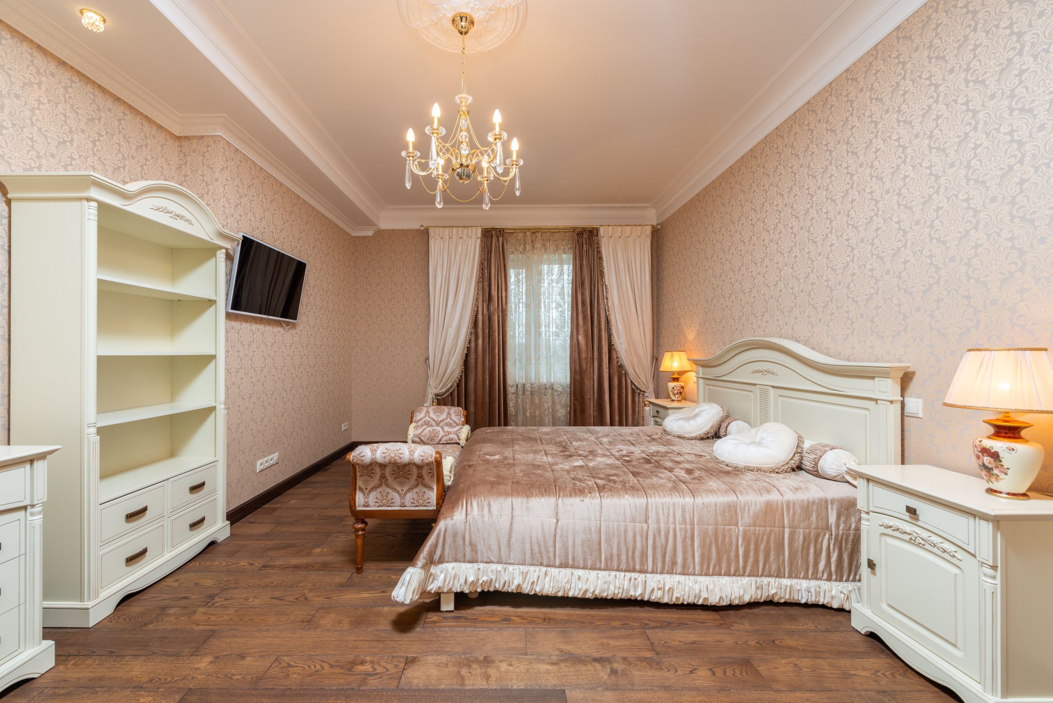 Cozy classic bedroom interior with elegant chandelier and luxurious furnishings.