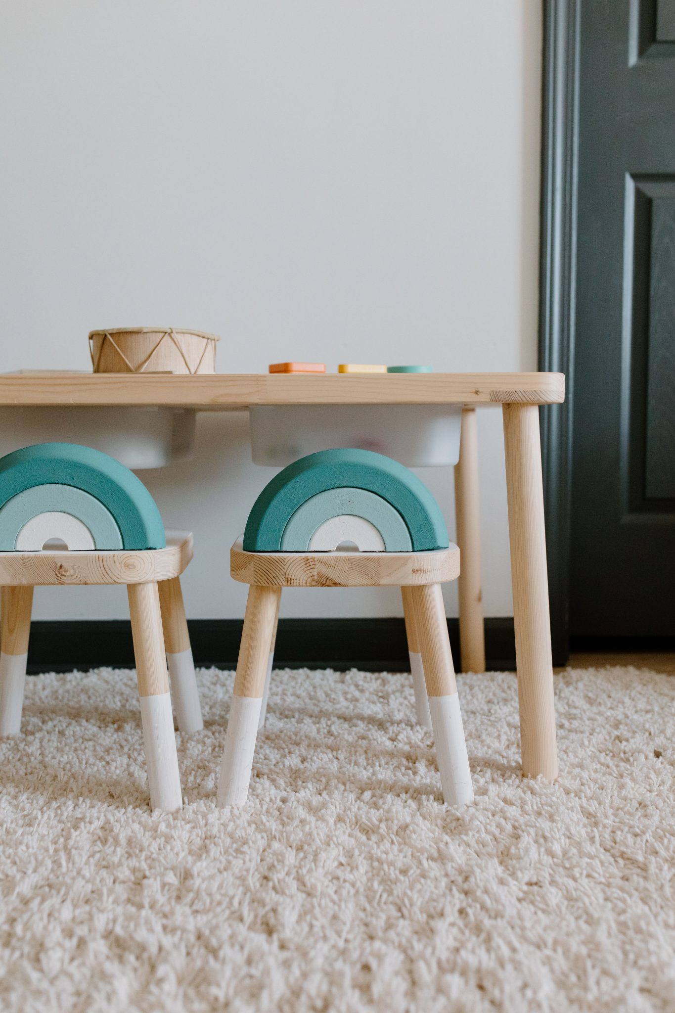 Cozy indoor play area with wooden table, colorful chairs, and educational toys on carpet.