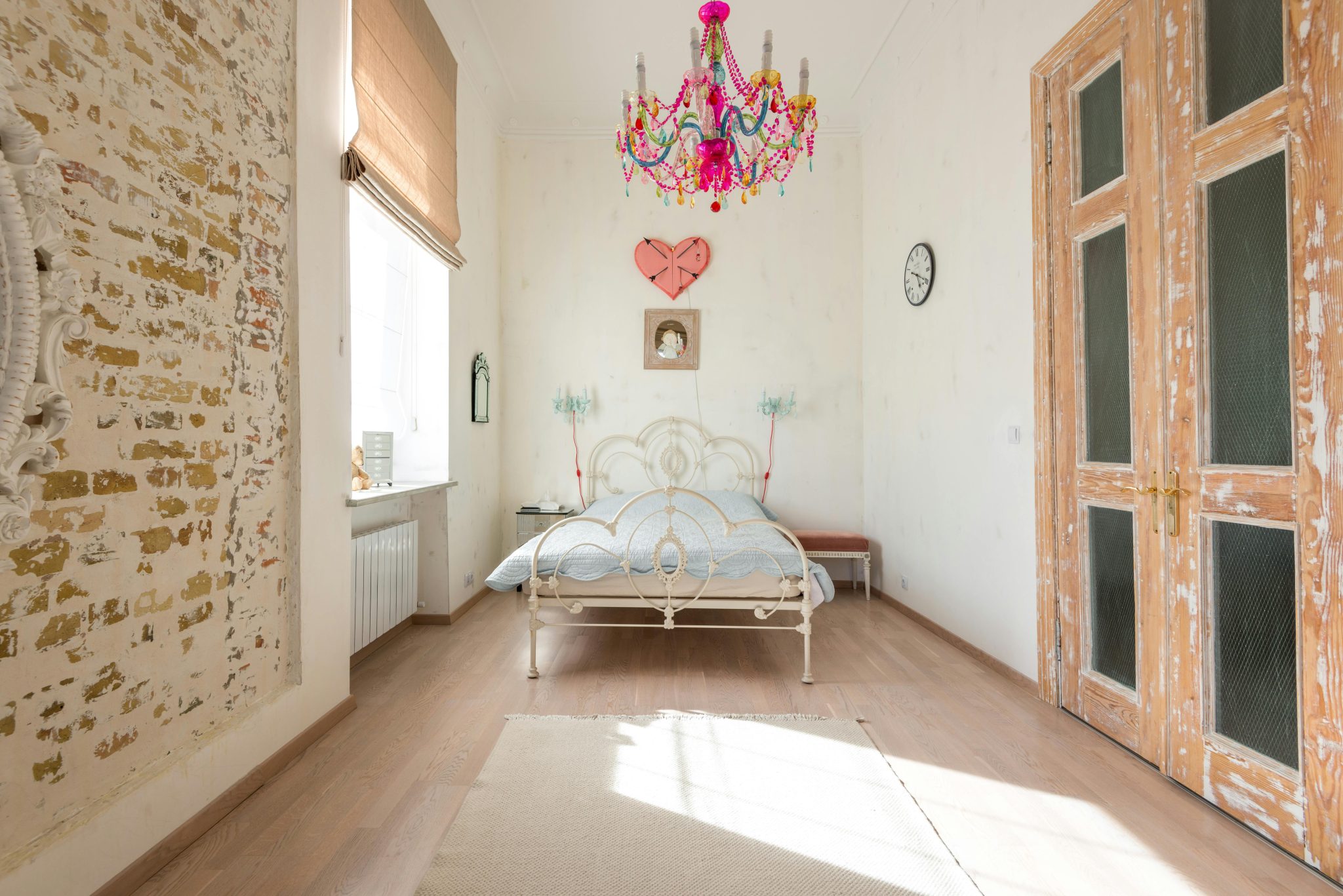 Cozy vintage-style bedroom featuring a colorful chandelier and rustic decor elements.
