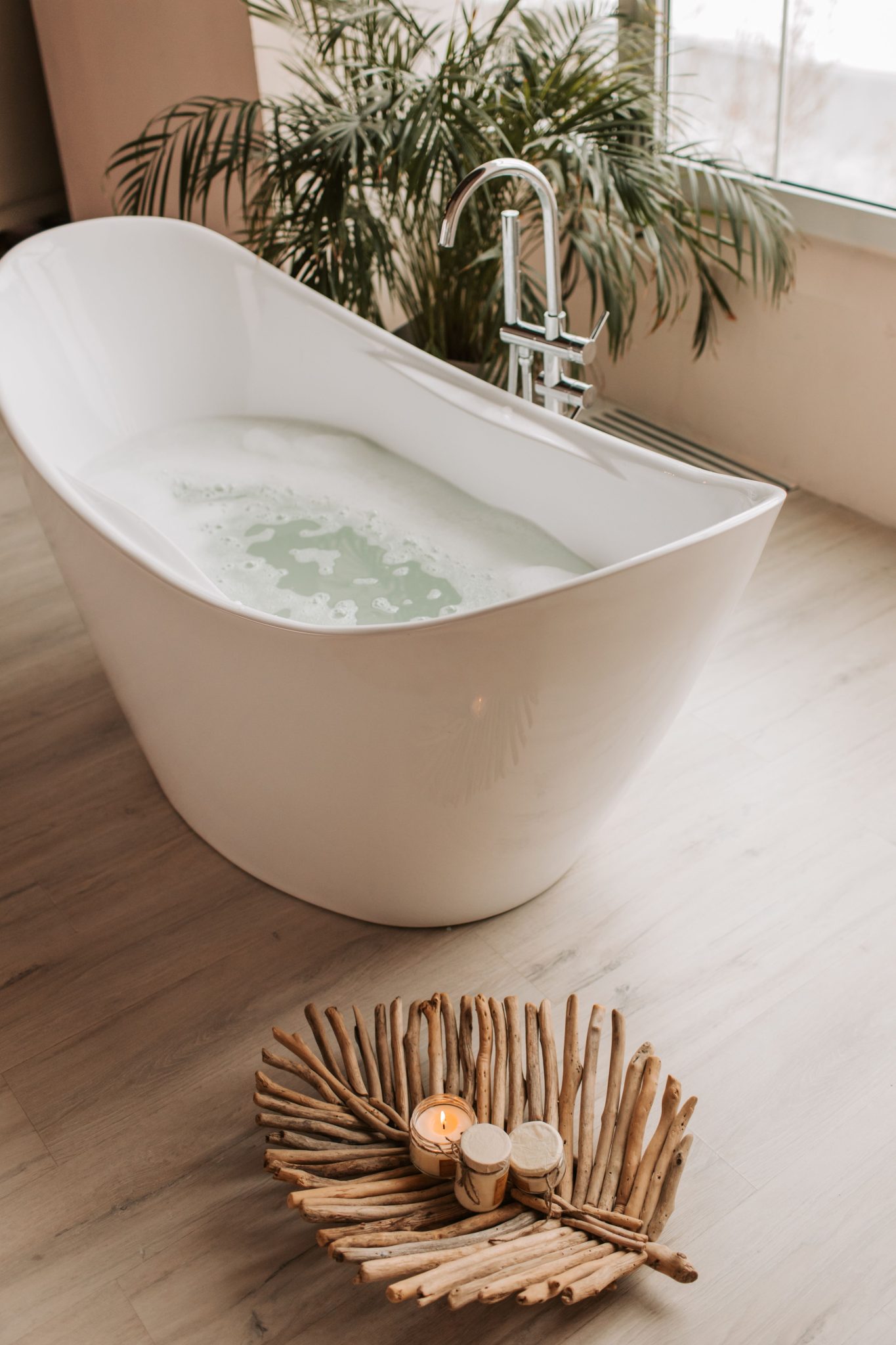 Elegant bathtub with candles and plants creating a calming spa-like ambiance.
