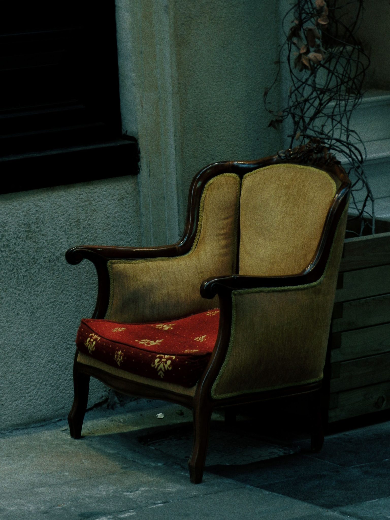 Elegant vintage armchair with floral patterns in a rustic, indoor environment. Warm, nostalgic feel.