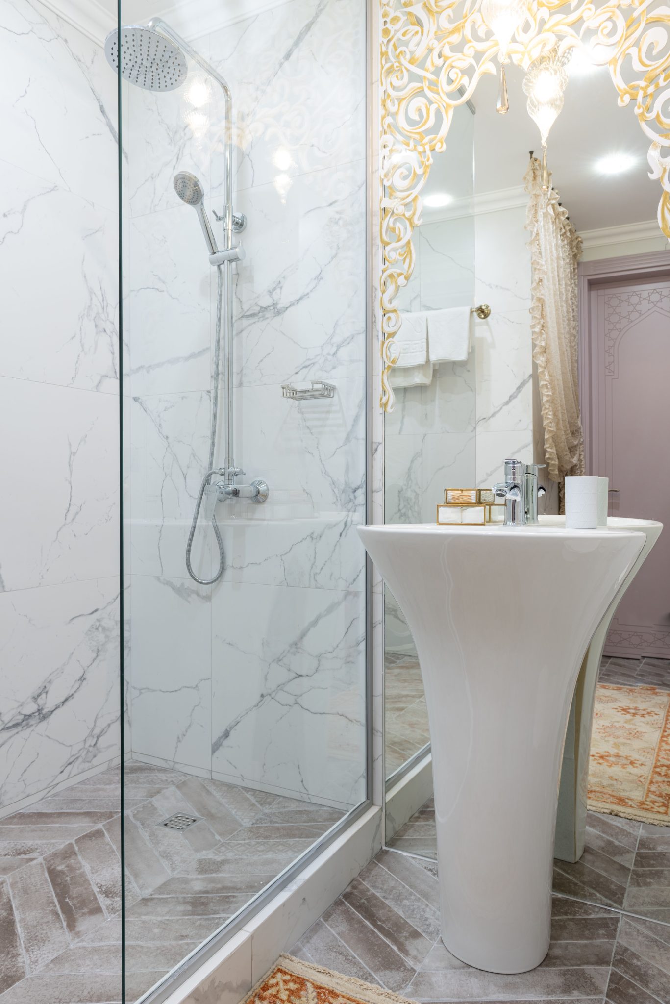 Interior of modern bathroom with transparent glass shower cabin near white sink placed near mirror with reflection of light room