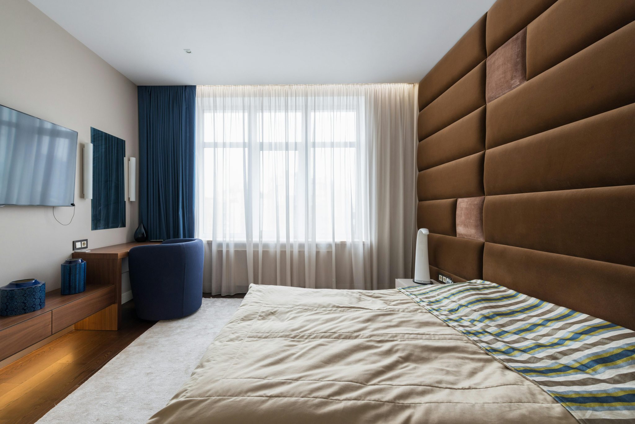 Interior of stylish bedroom with comfortable large bed in contemporary apartment in daytime