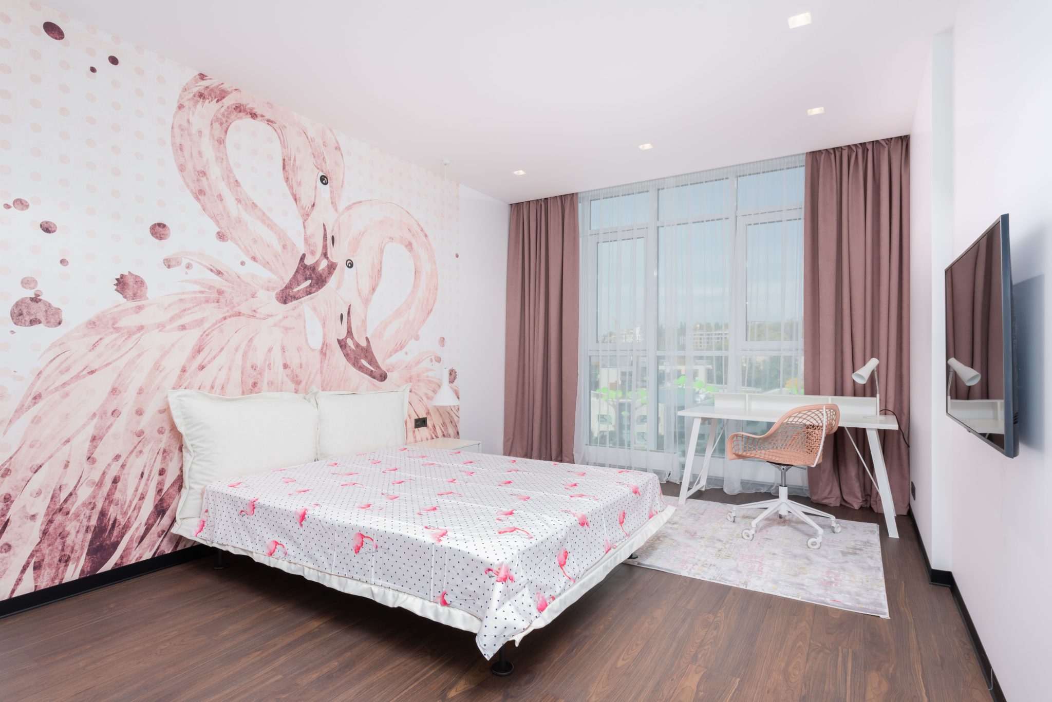 Interior of stylish room with soft bed against TV set and table with chair near window