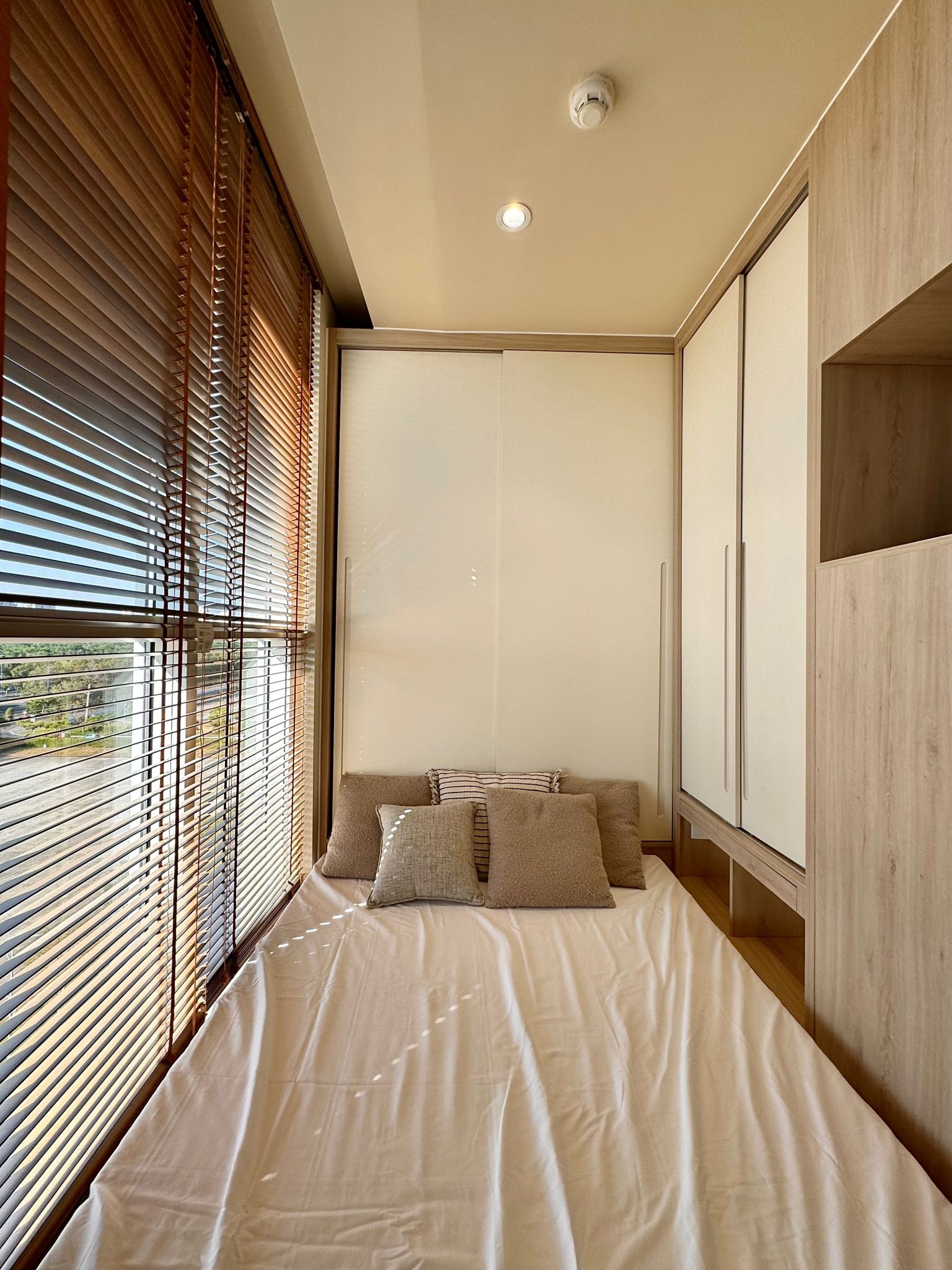 Inviting and sunlit modern bedroom featuring gentle natural light, minimalist decor, and cozy pillows.