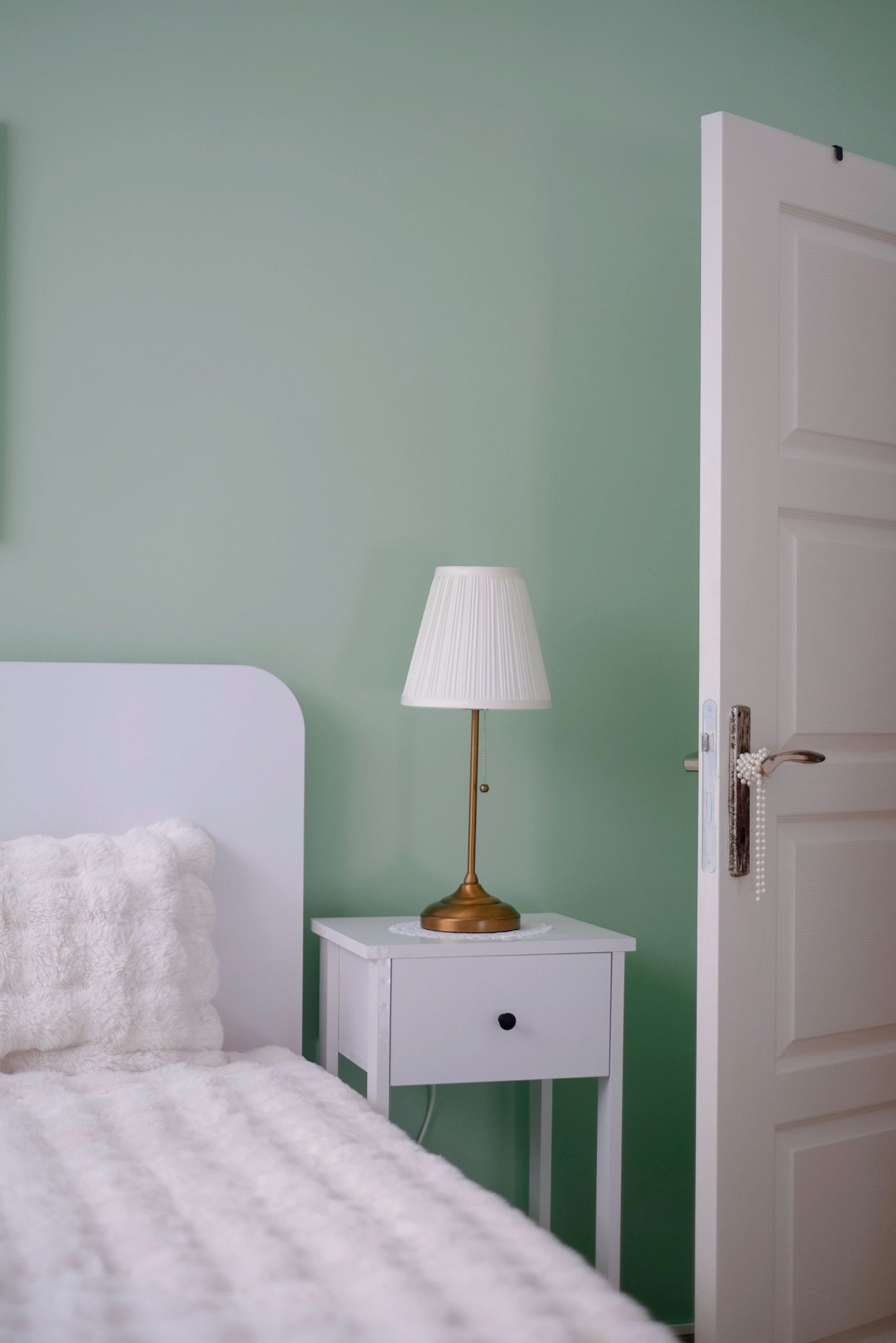 Inviting bedroom scene featuring a white lamp and plush bedding, perfect for a serene atmosphere.