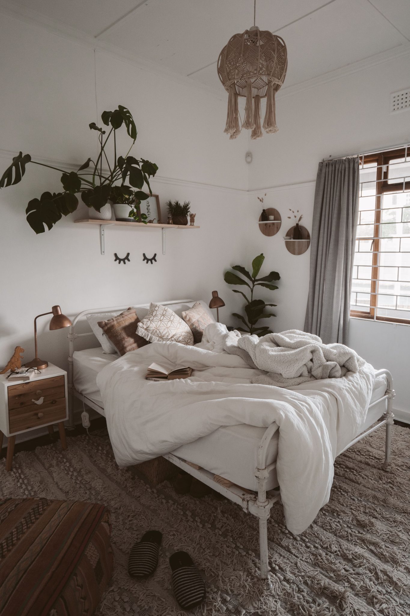 Inviting bedroom with cozy Scandinavian decor, featuring a lush indoor plant and textured bedding.
