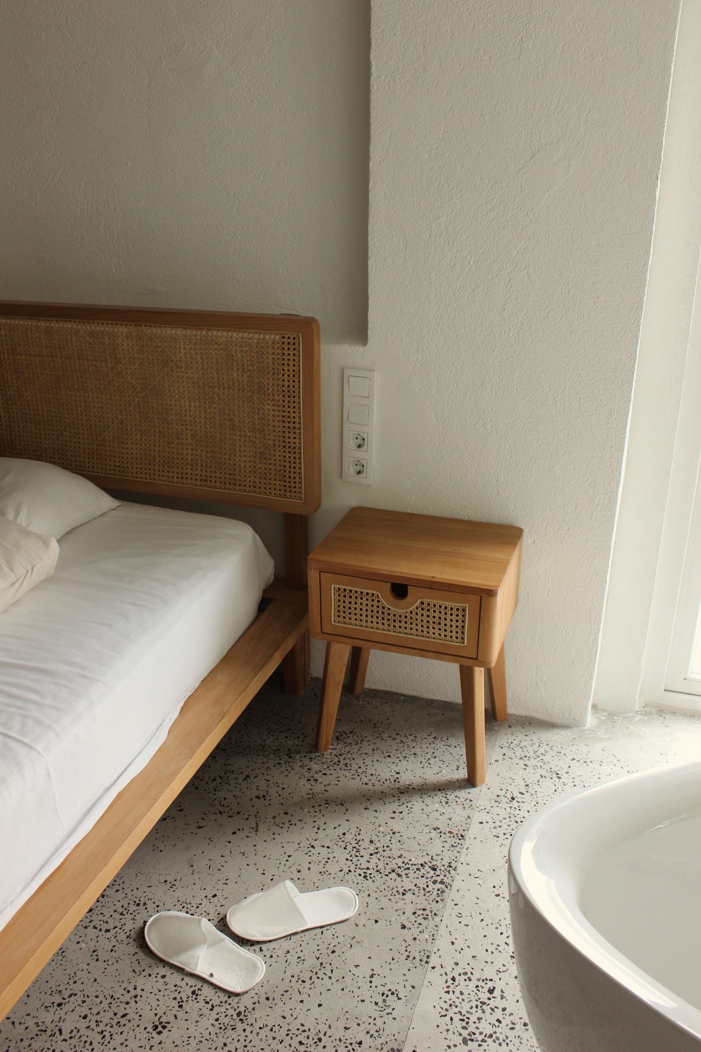 Inviting minimalist bedroom with wooden bed frame and side table. Calm and serene.