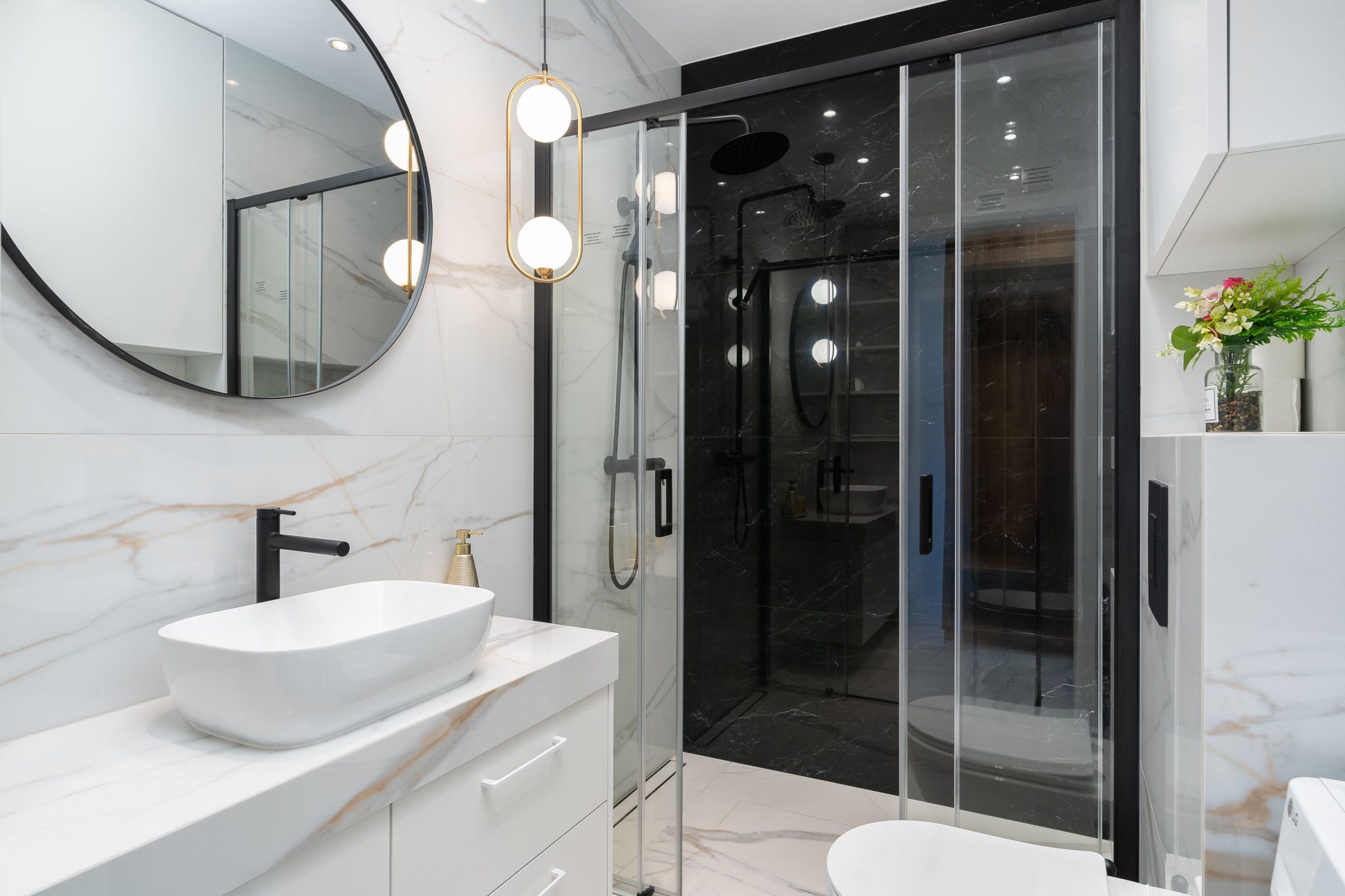 Sleek modern bathroom featuring a marble countertop, stylish circular mirror, and elegant lighting.