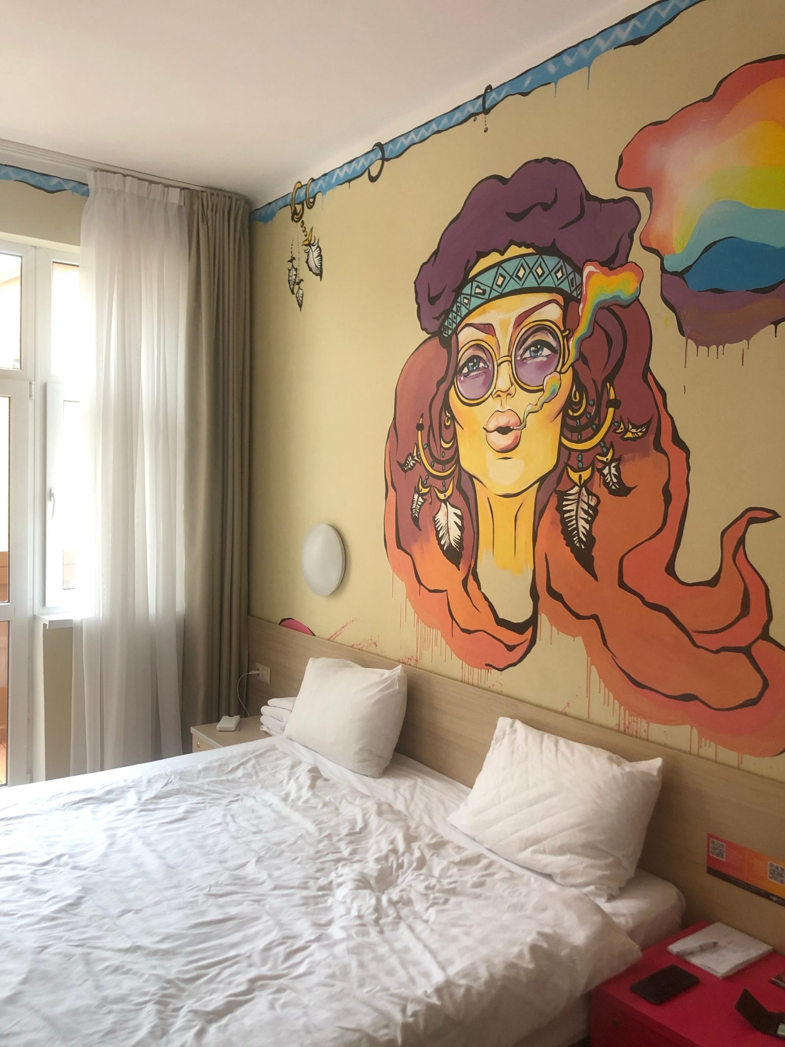 Stylish bohemian bedroom featuring vibrant hippie mural and cozy interior design.