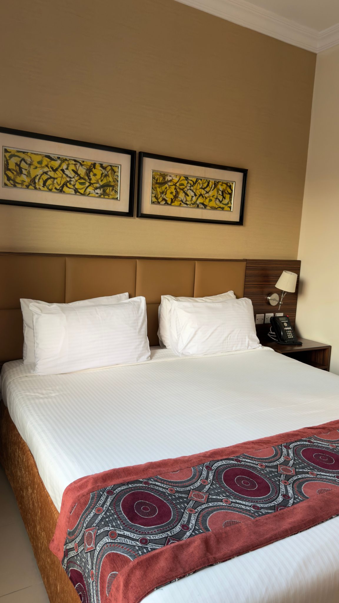 Stylish hotel room with double bed, elegant decor, and artwork.