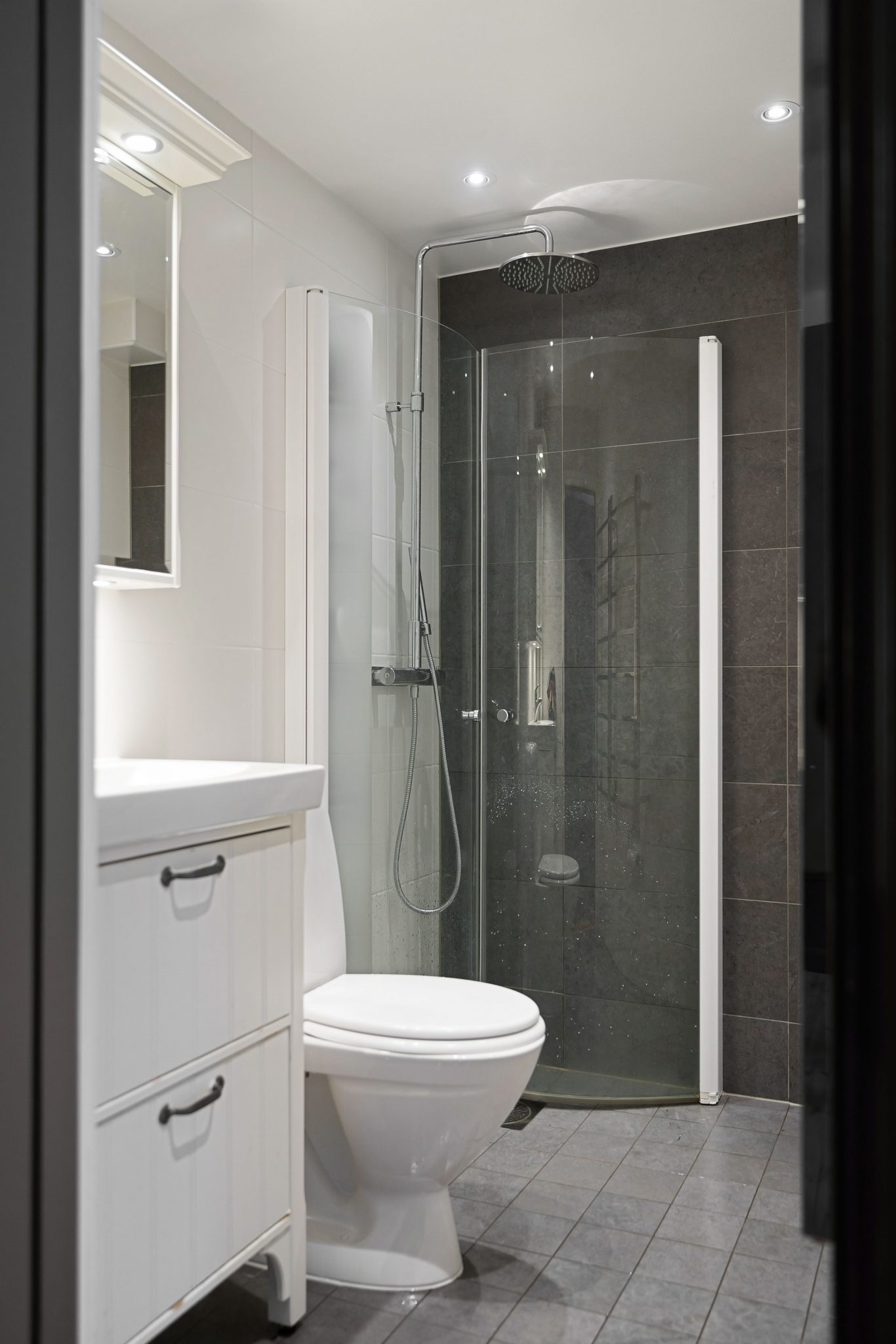 Stylish minimalist bathroom featuring a glass shower and sleek white fixtures.