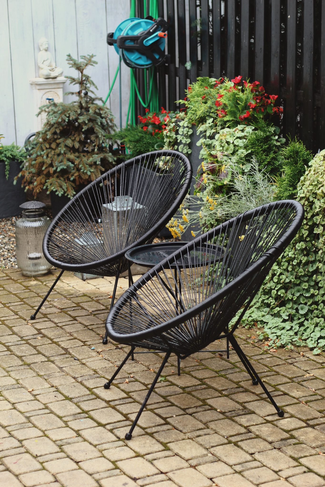 Stylish outdoor patio with modern black wicker chairs and lush greenery.
