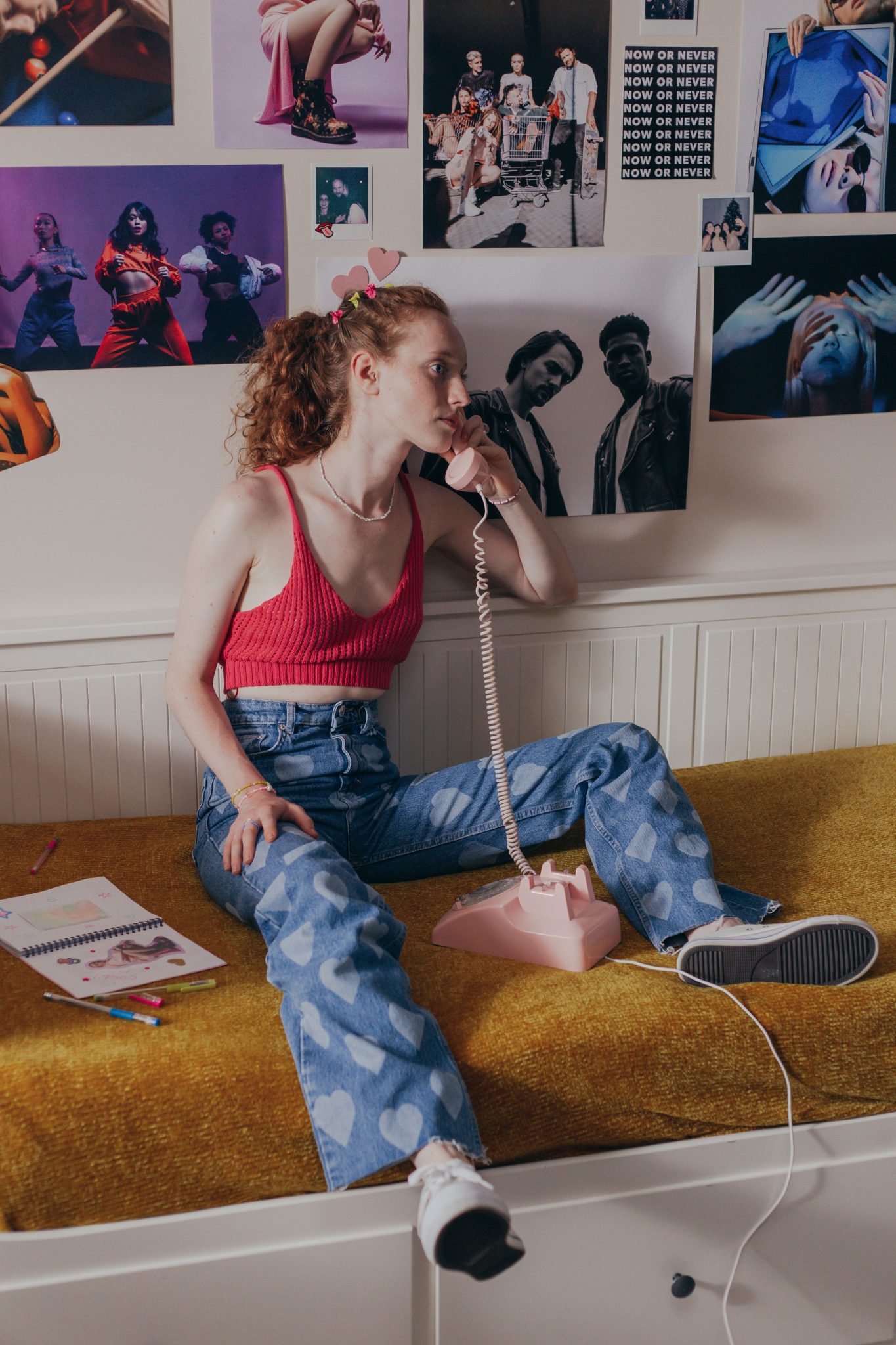 Teenage girl in a 90s-inspired bedroom talking on a landline phone, surrounded by posters.
