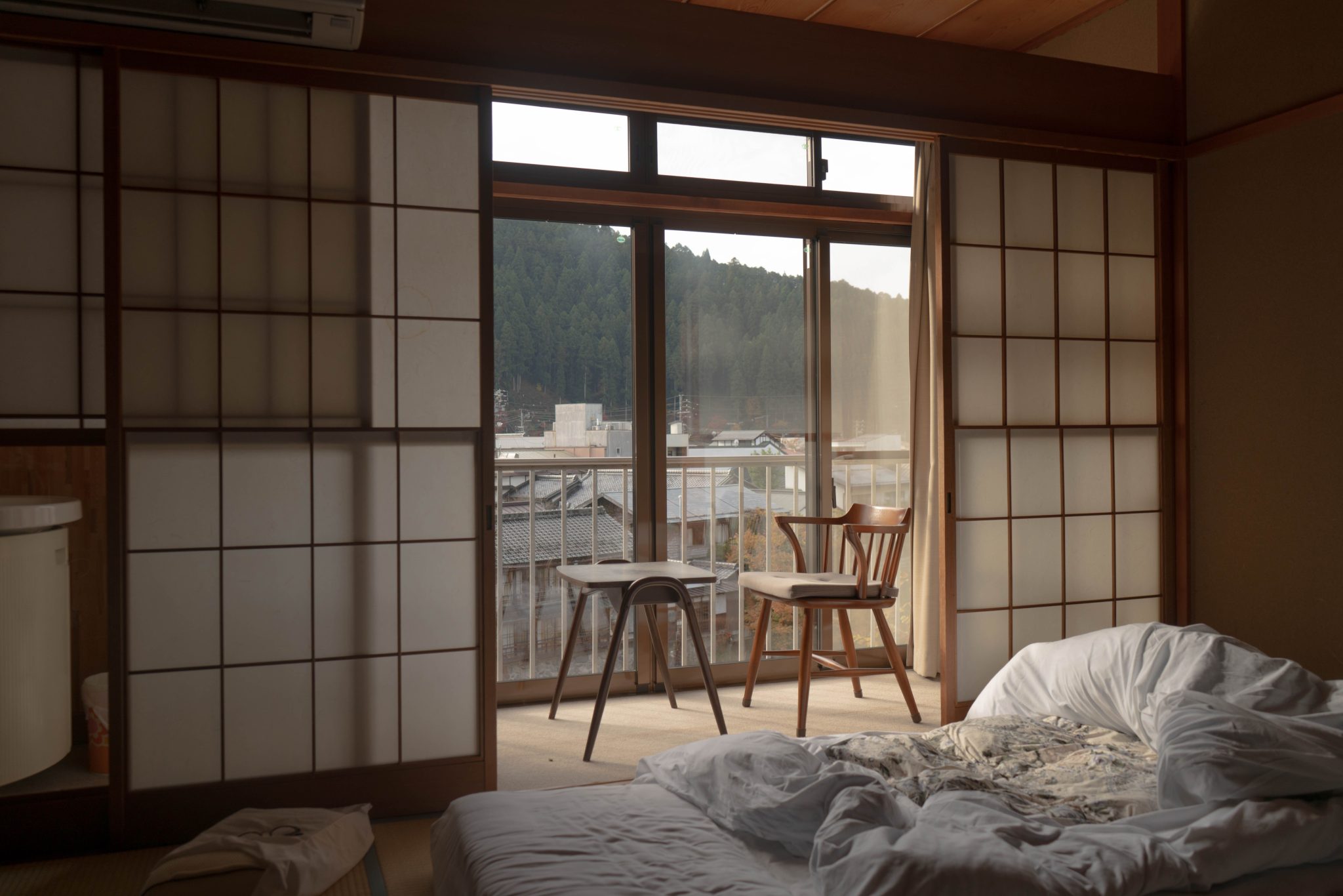 Traditional Japanese bedroom with wooden furniture and sliding doors overlooking a scenic view.
